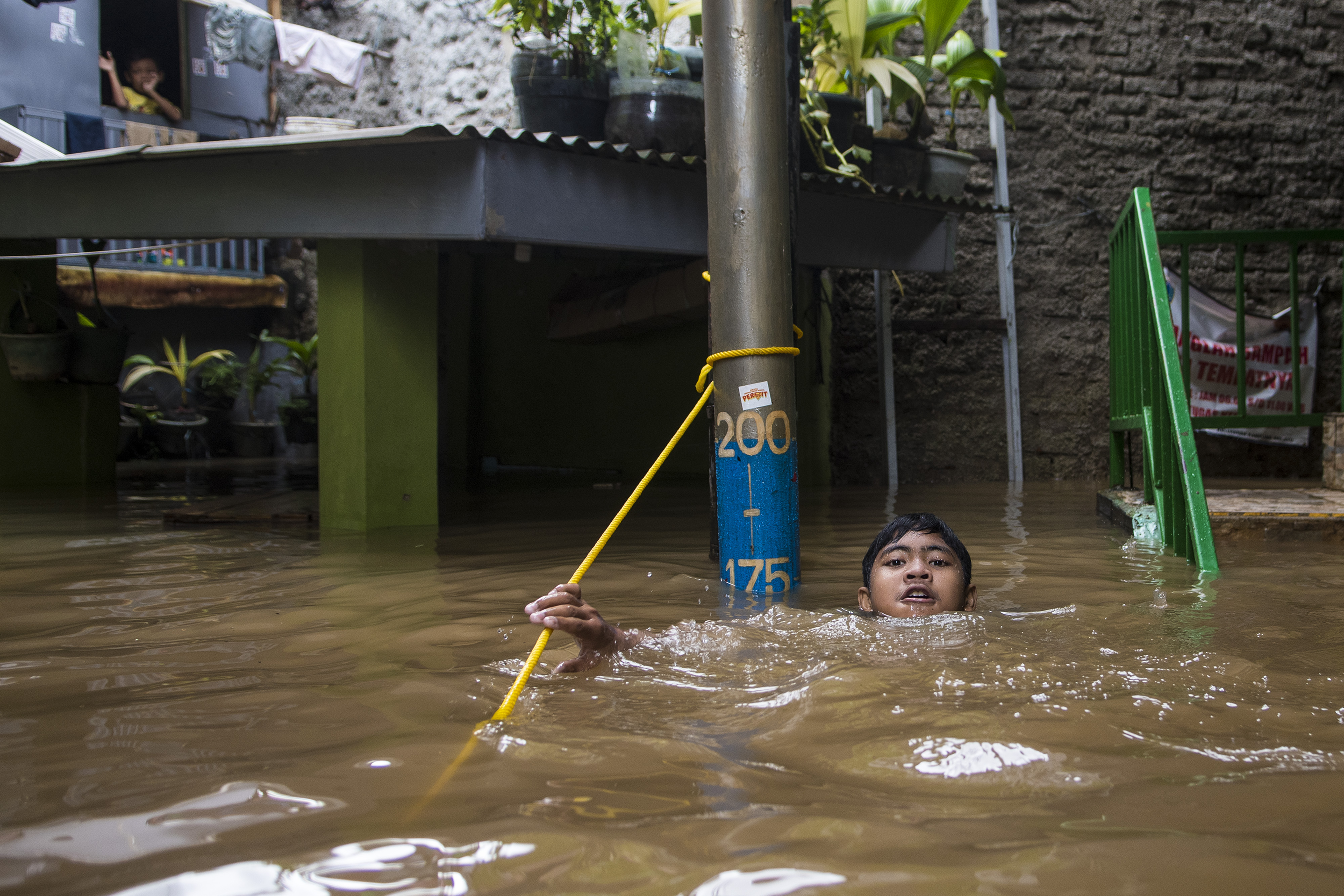 Warga berjalan melewati banjir di kawasan pemukiman penduduk, Kebon Pala.