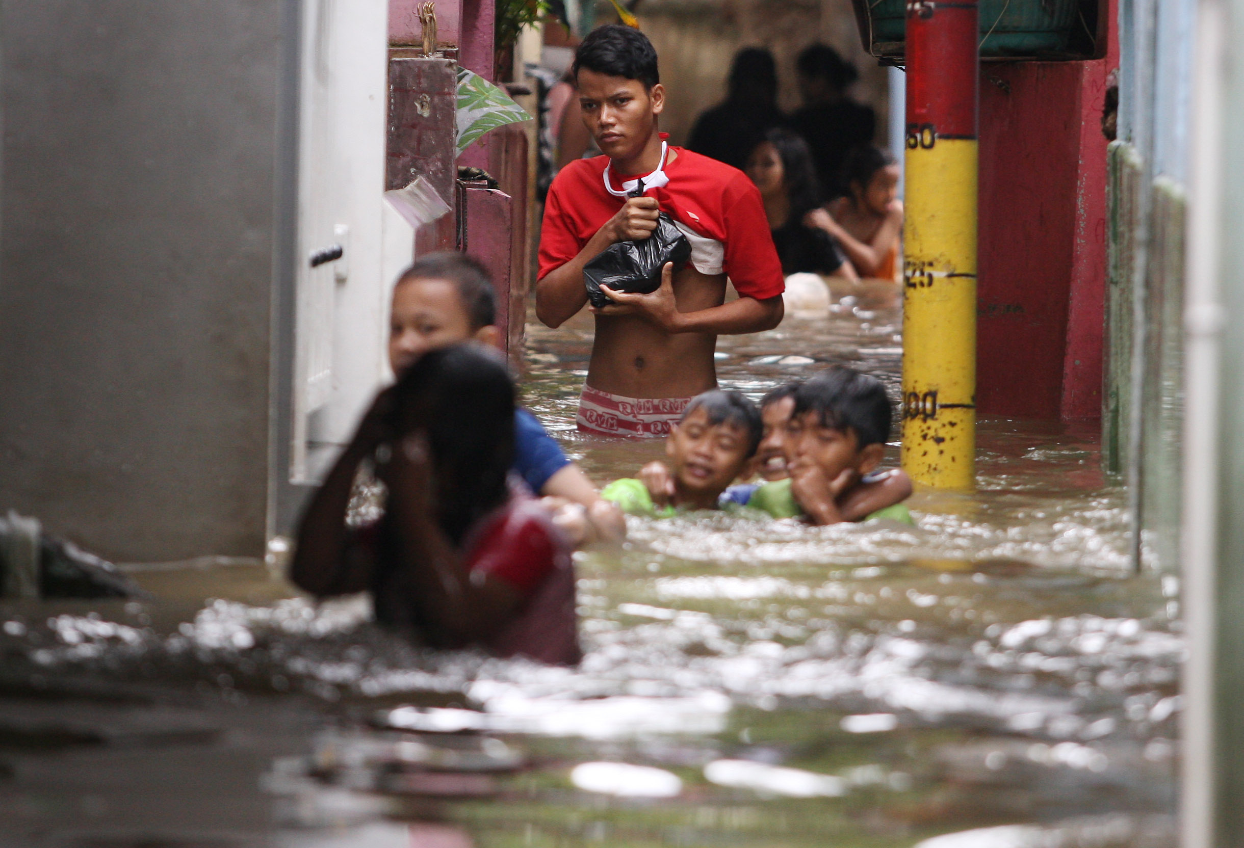 Warga beraktivitas di tengah banjir yang mengepung RT 13/RW 04, Kebon Pala, Kecamatan Jatinegara, Jakarta Timur, Senin (27/02/2023).