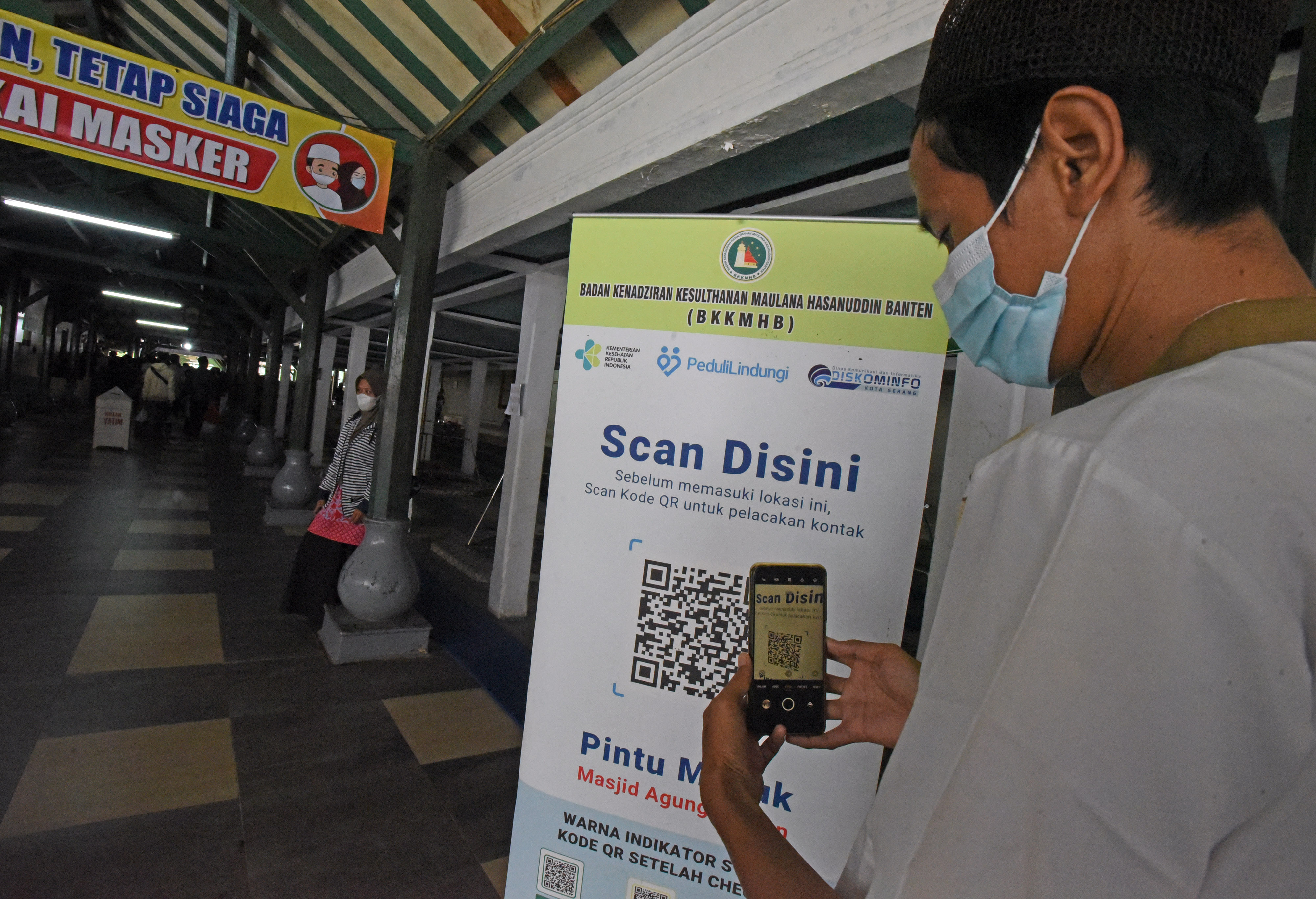 Pengunjung memindai aplikasi PeduliLindungi sebelum memasuki kawasan Wisata Religi di Kompleks Kesultanan Banten di Kasemen, Serang, Banten.