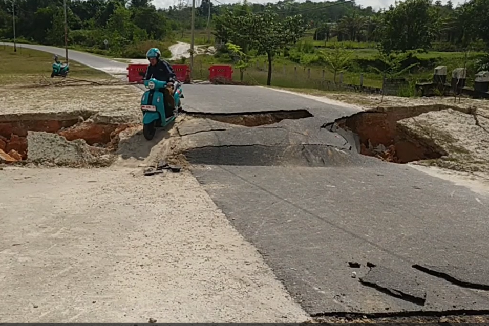 Warga melalui jembatan ambles dengan sepeda motor.