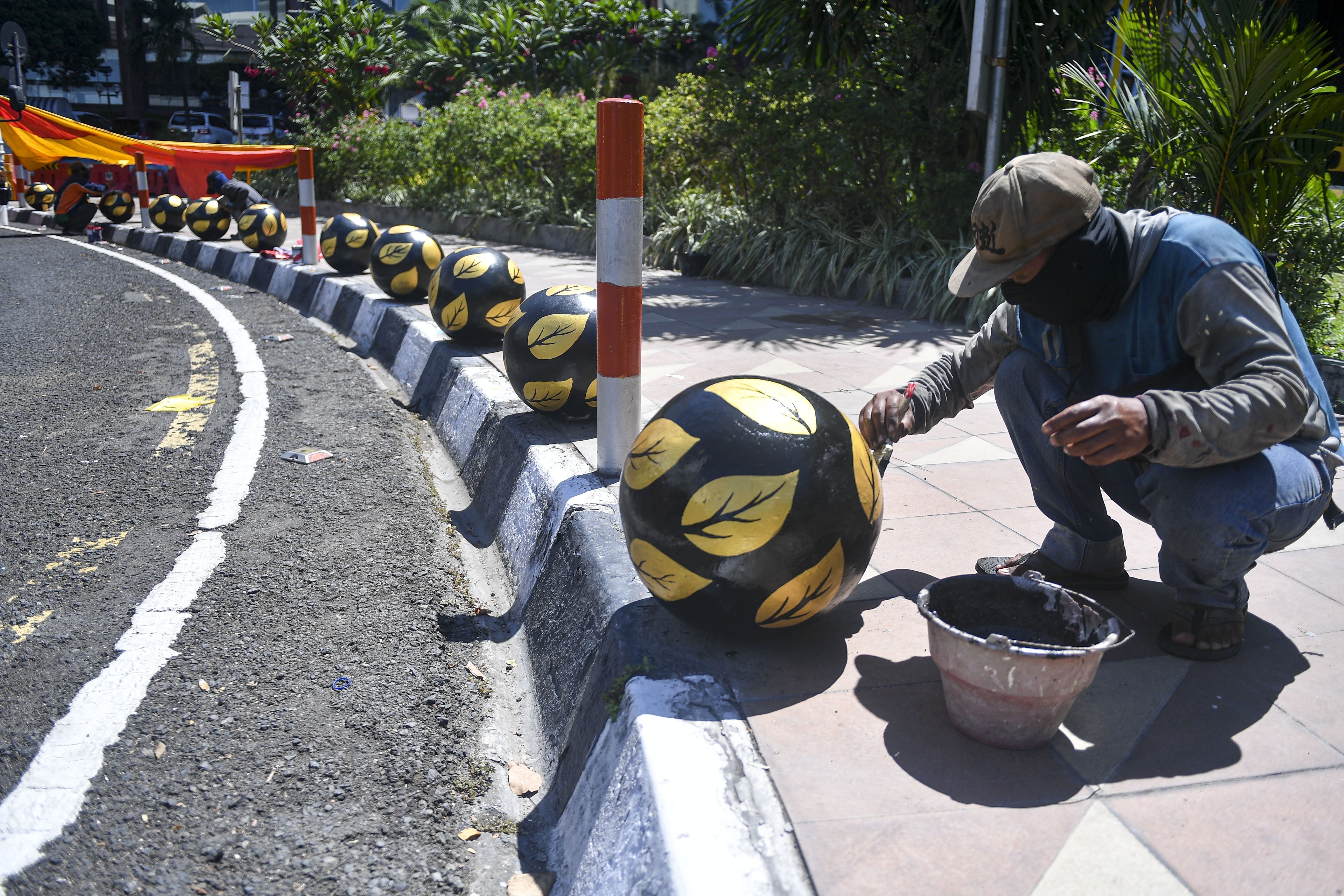Petugas kebersihan mengecat bollard di jalur pedestrian wilayah Surabaya. 