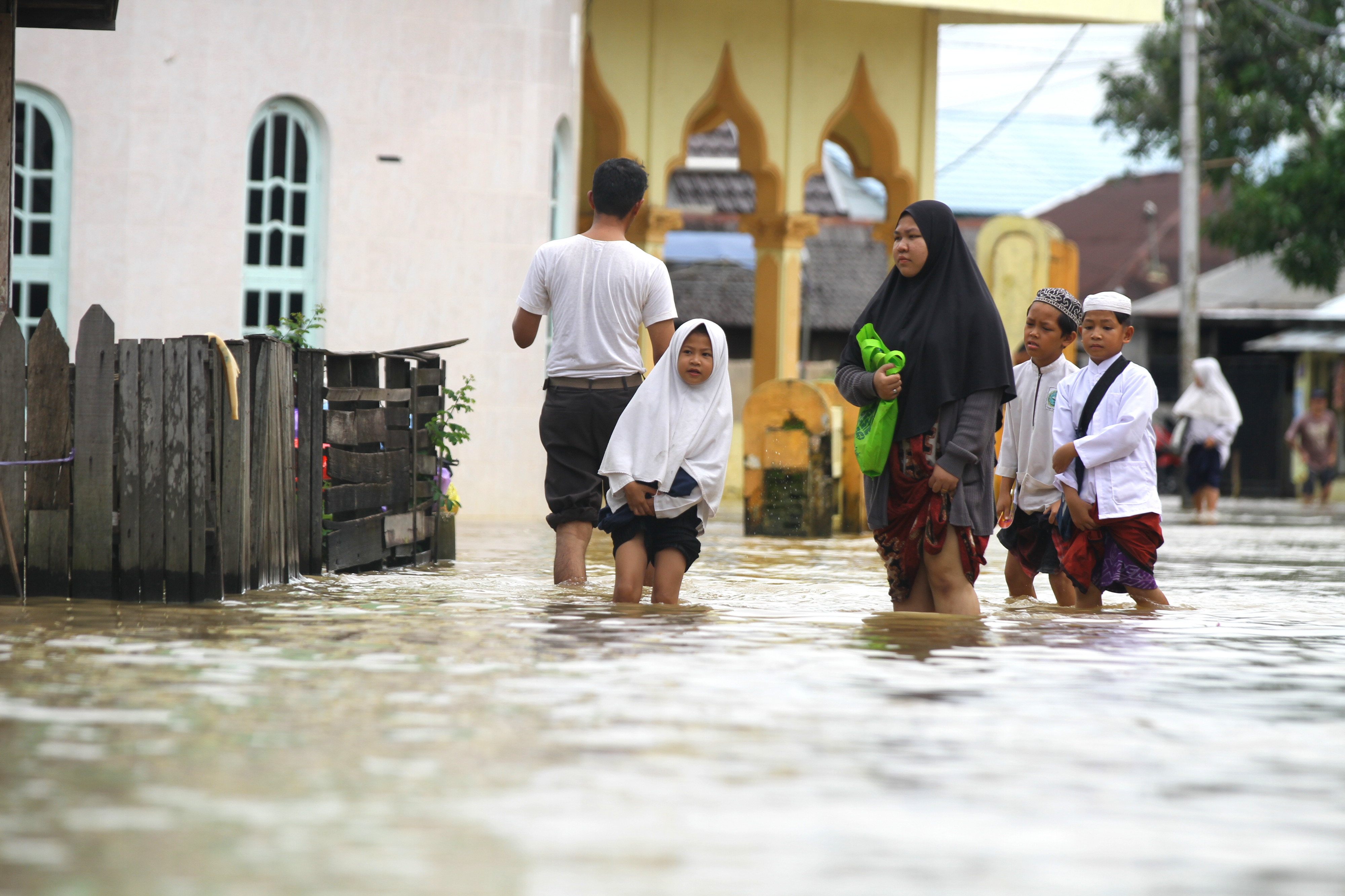 Warga melintasi jalan yang tergenang banjir di Desa Dalam Pagar Ulu, Kabupaten Banjar, Kalimantan Selatan, Senin (27/2).