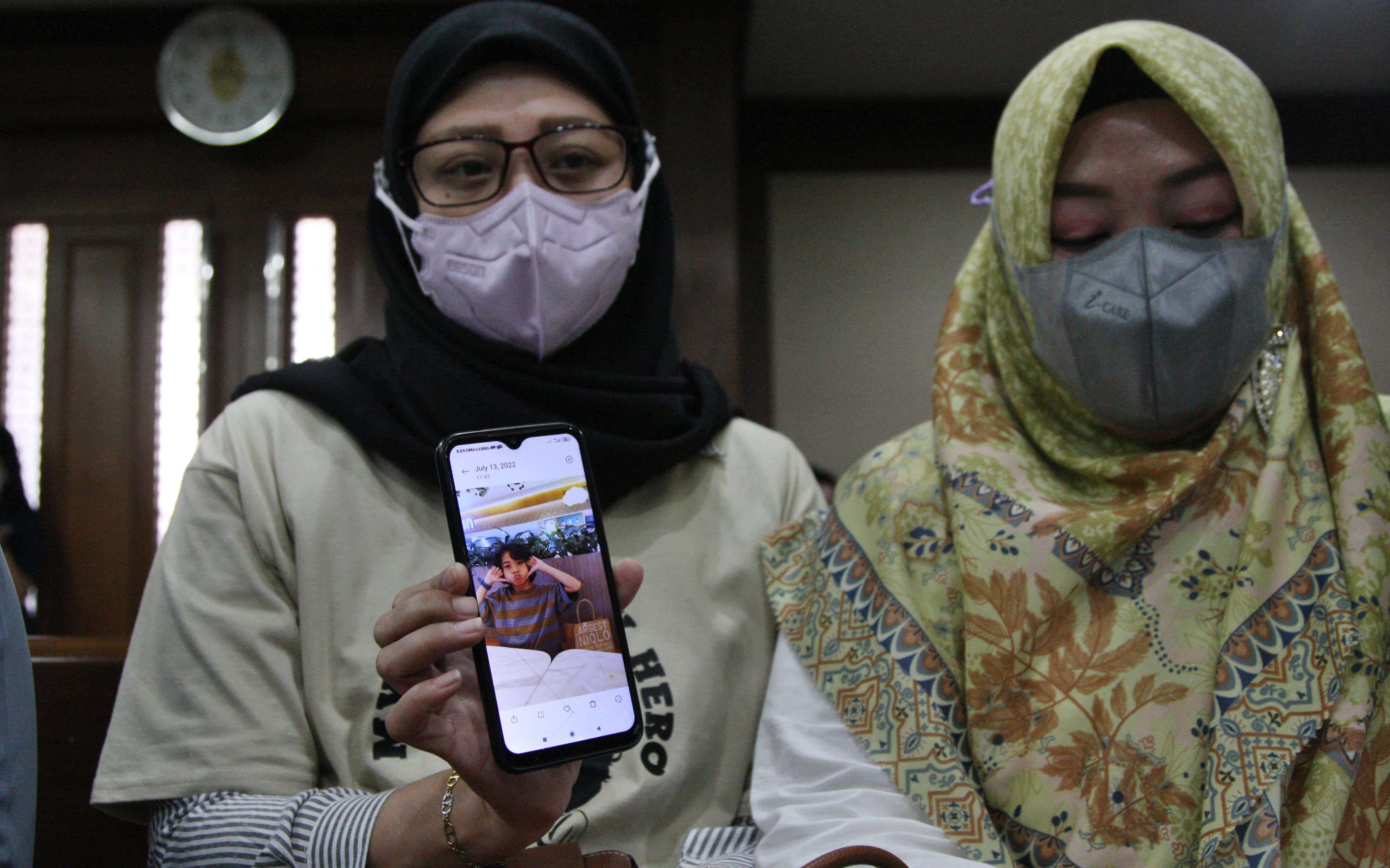 Safitri (kiri) memperlihatkan foto putranya bernama Panghegar berusia 8 tahun yang masih terbaring sakit akibat gagal ginjal akut.