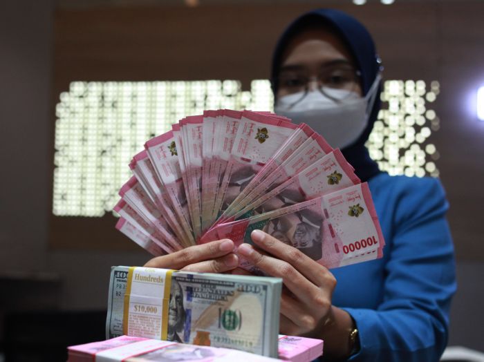  Petugas menunjukkan uang dolar AS dan uang rupiah di salah satu kantor cabang PT Bank Mandiri Persero Tbk, Jakarta.