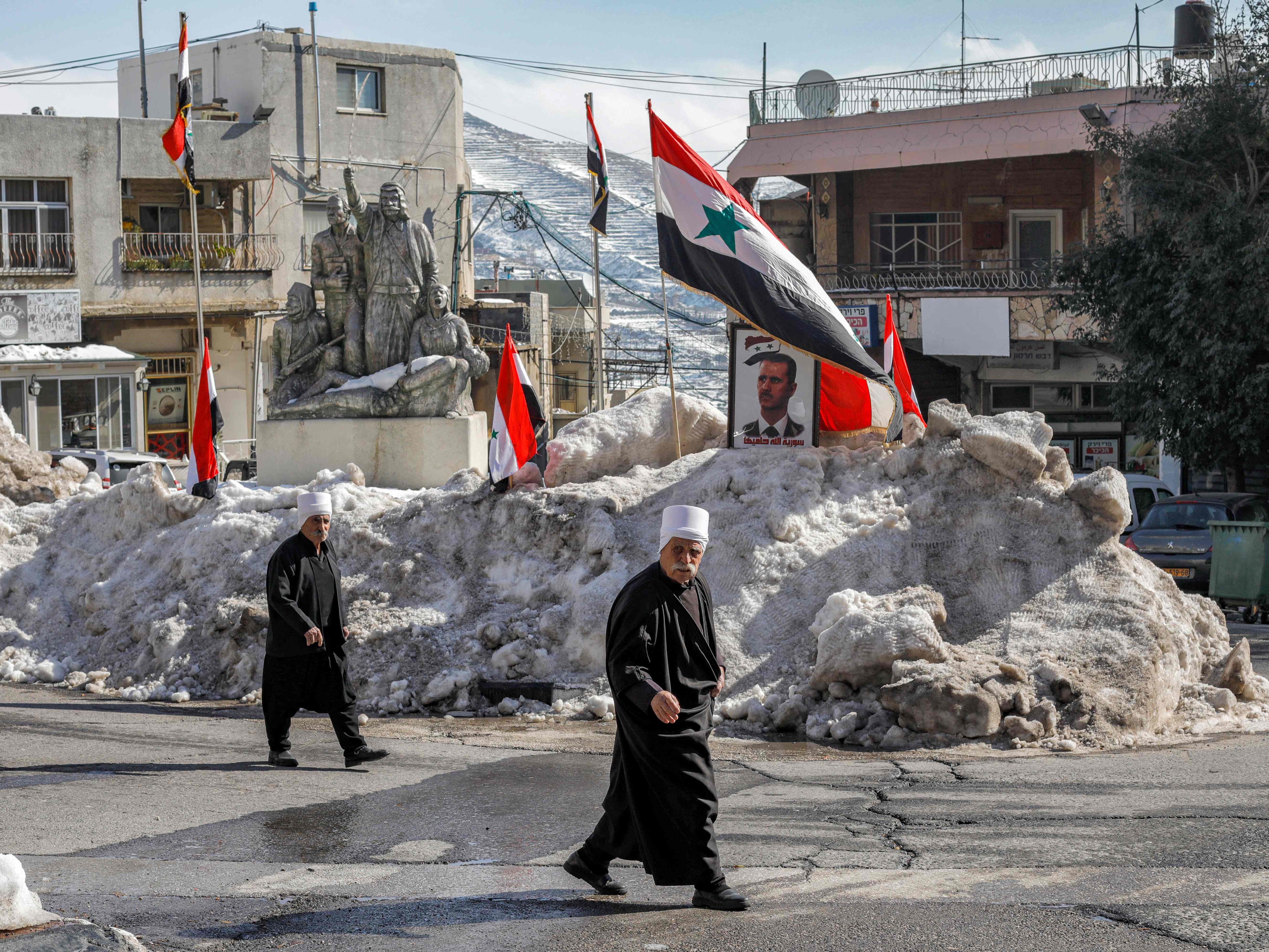 Penduduk Druze di Dataran Tinggi Golan berjalan melewati bendera Suriah dan potret Presiden Suriah Bashar al-Assad.