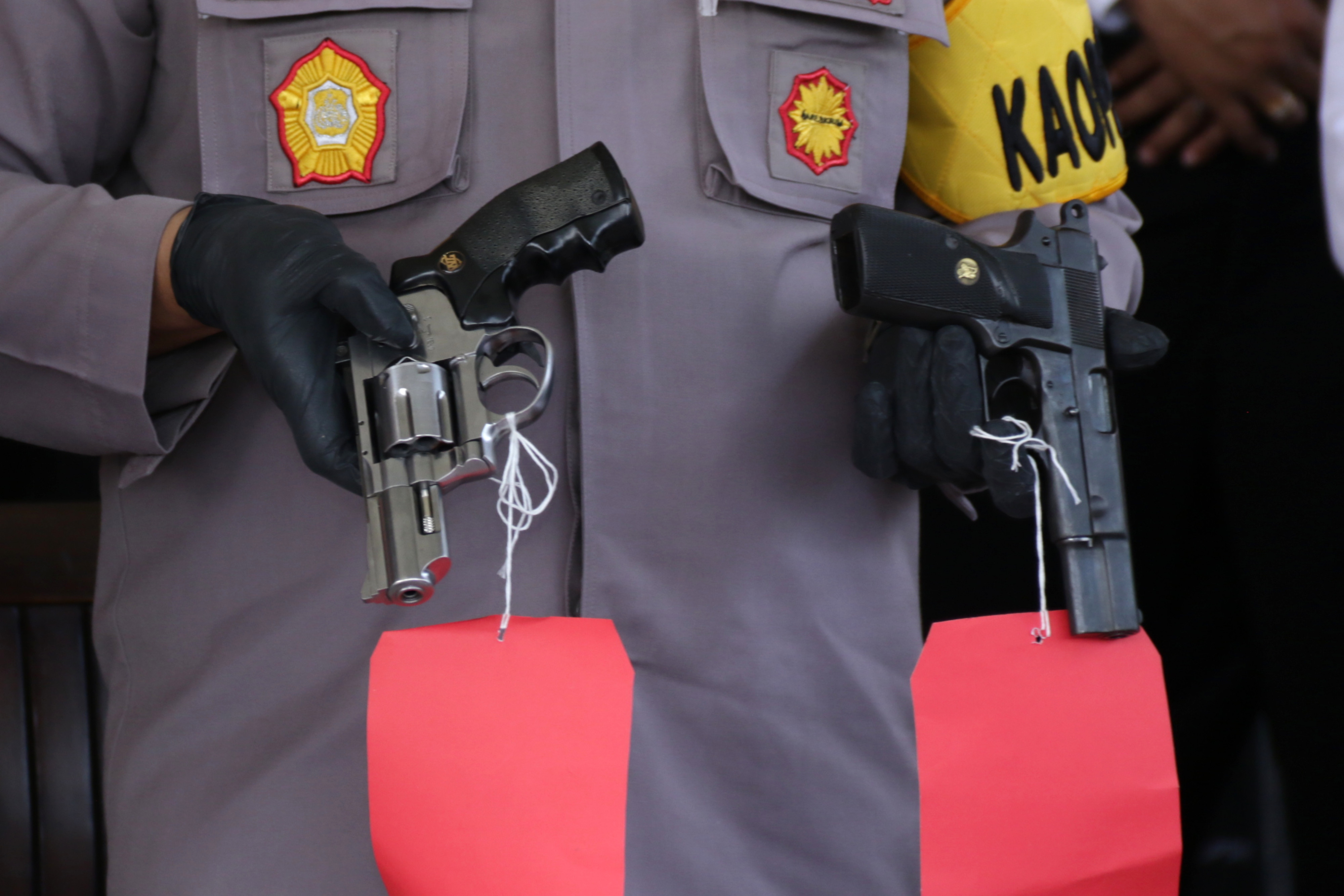 Ilustrasi petugas kepolisian menunjukkan barang bukti senjata api.