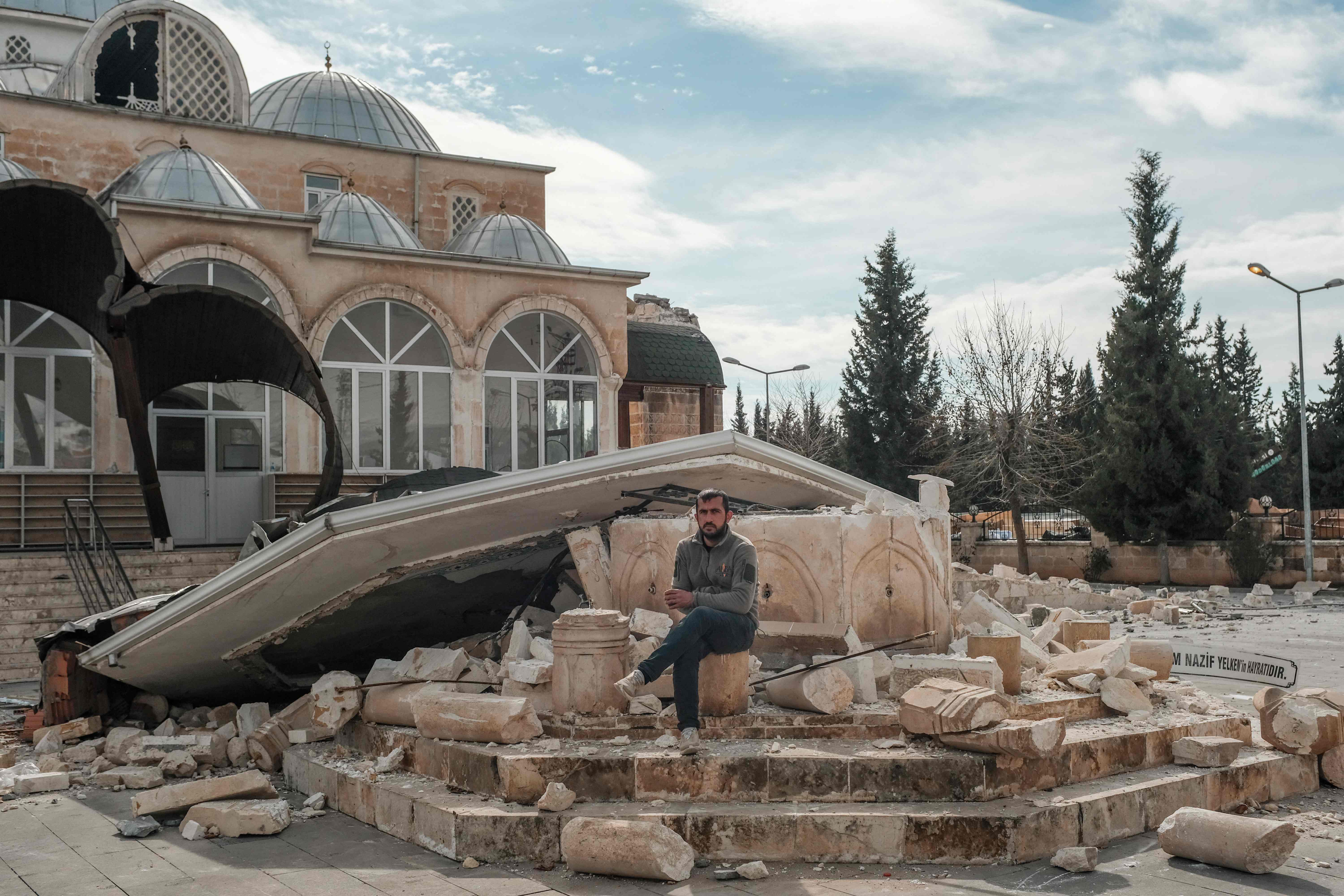 Seorang warga berada di antara reruntuhan sebuah masjid di Adiyaman, Turki.