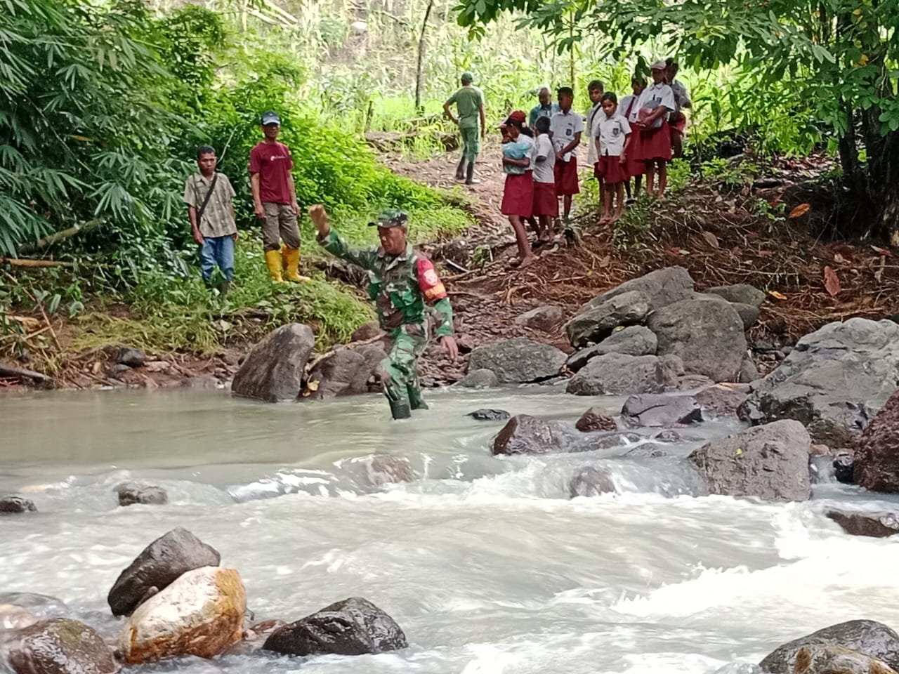 Babinsa Serka Bertholomeus Berek membantu anak sekolah menyeberangi sungai