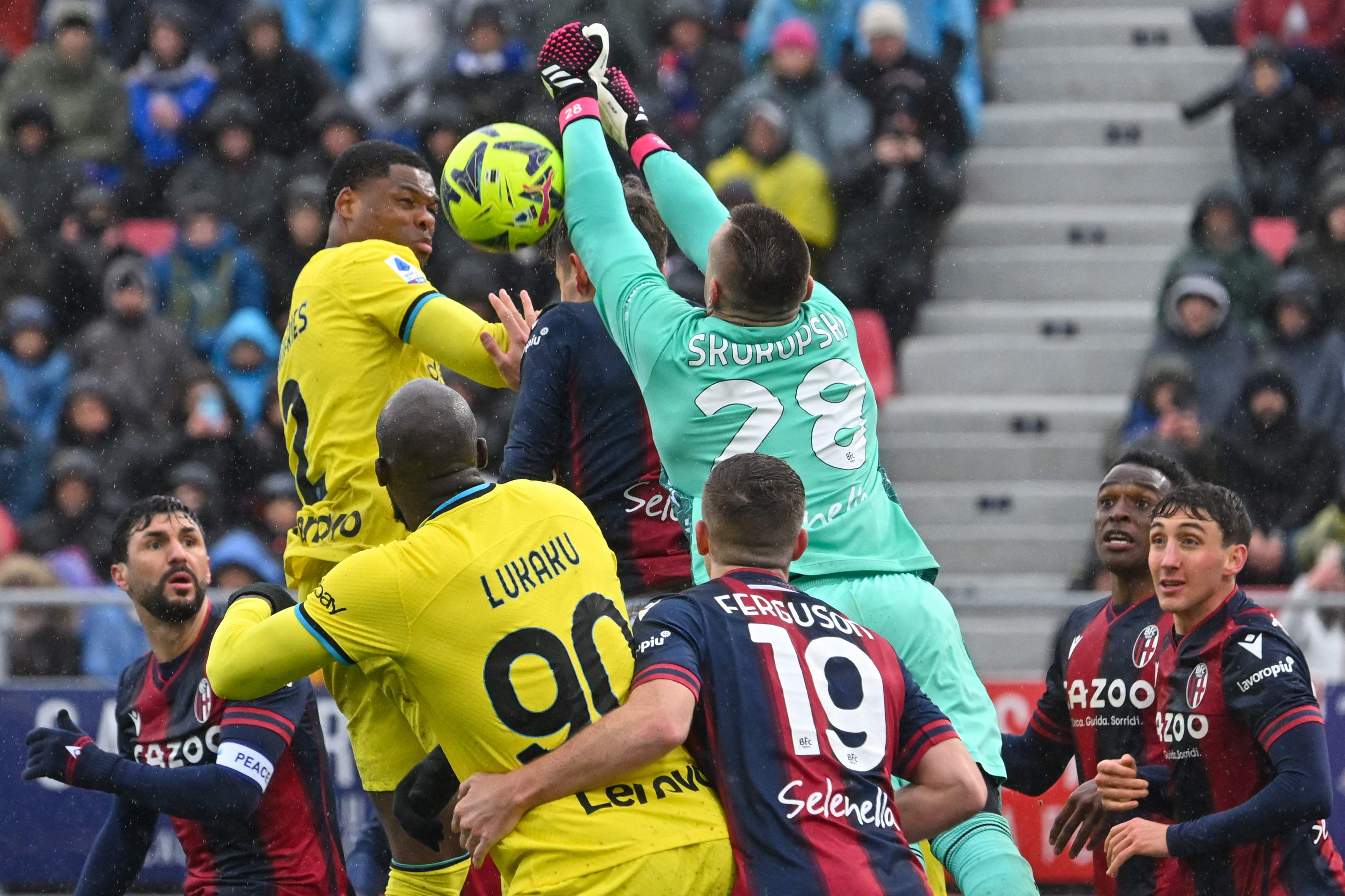 Gelandang Inter Milan Denzel Dumfries berebut bola udara dengan kiper Bologna Lukasz Skorupski dalam laga lanjutan Seri A, Minggu (26/2).