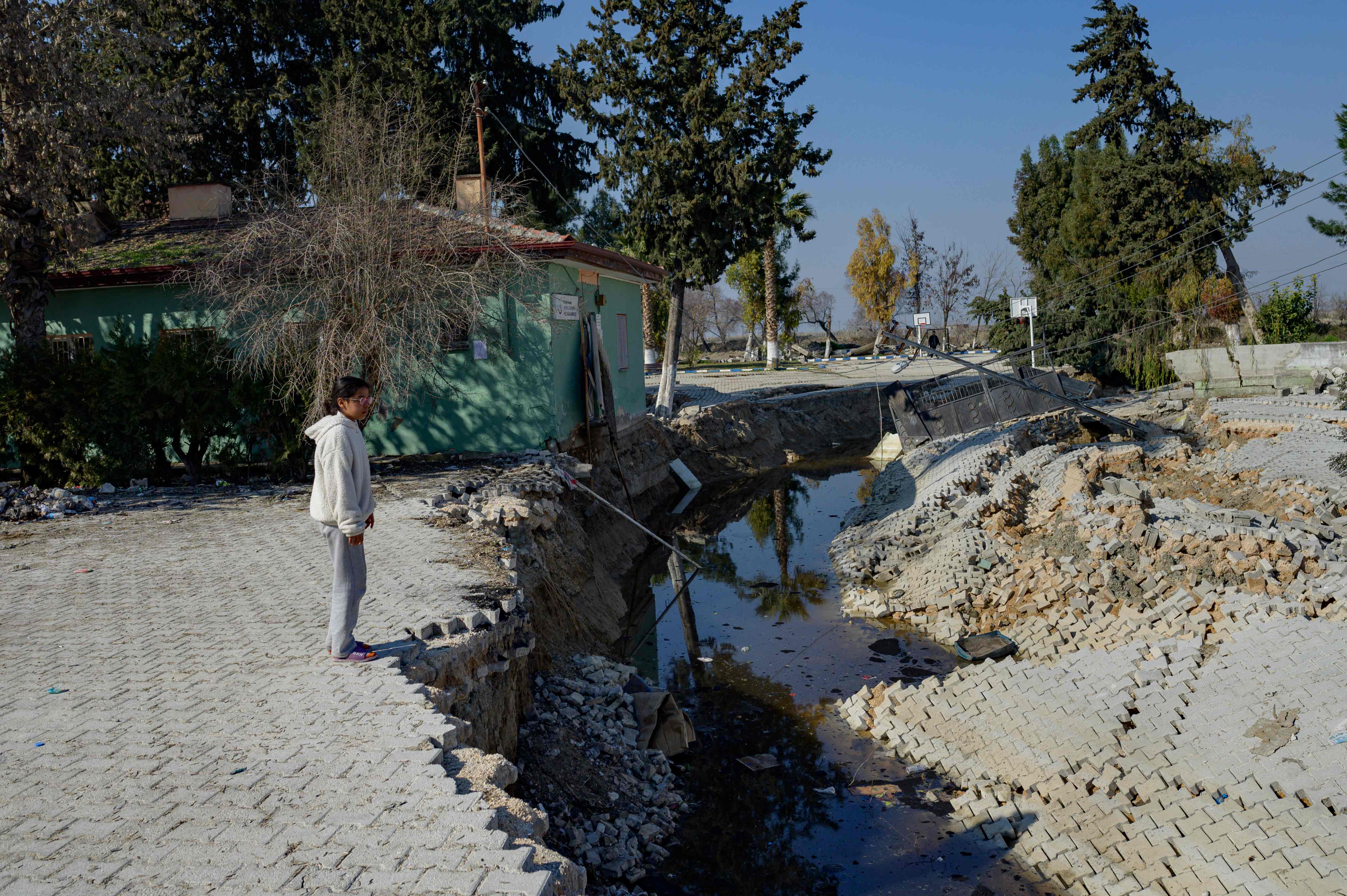 Seorang gadis berdiri memandangi tepi retakan di jalanan berbatu di Desa Demirkopru.