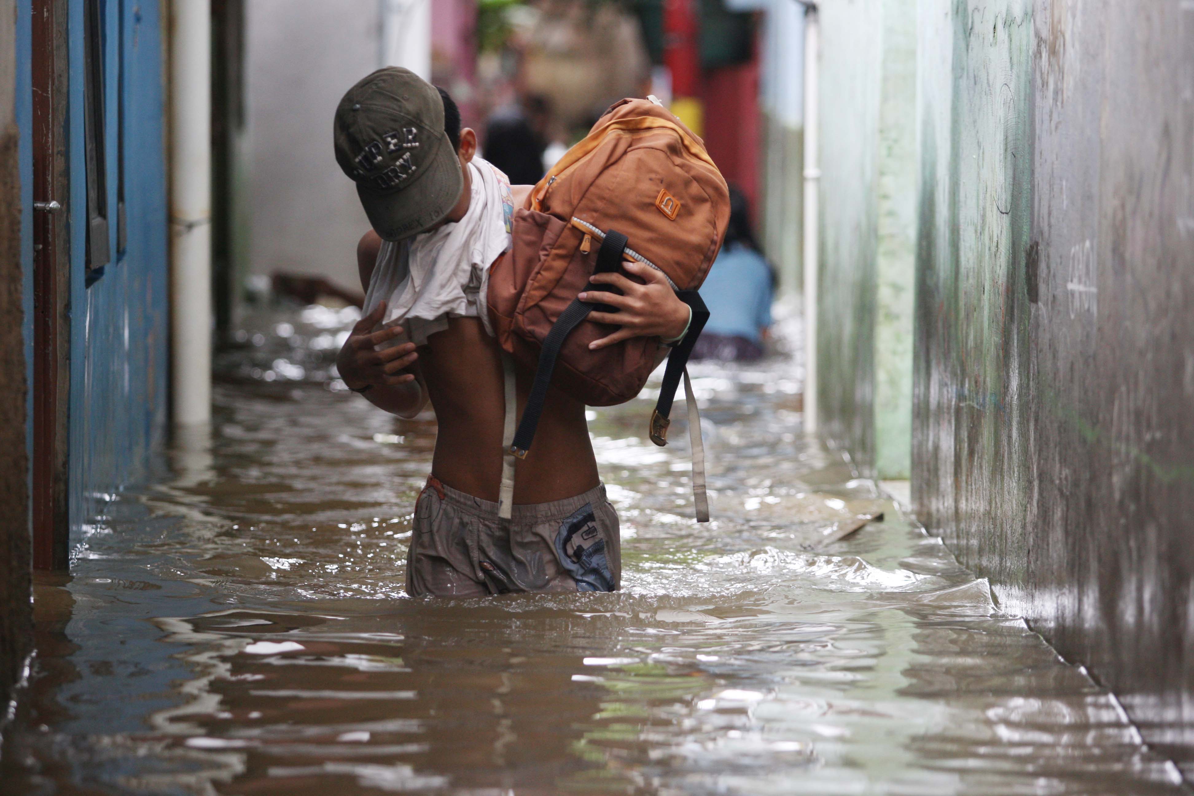 Seorang pelajar pulang sekolah menyusuri banjir yang mengepung kawasan Kebon Pala, Kecamatan Jatinegara, Jakarta Timur