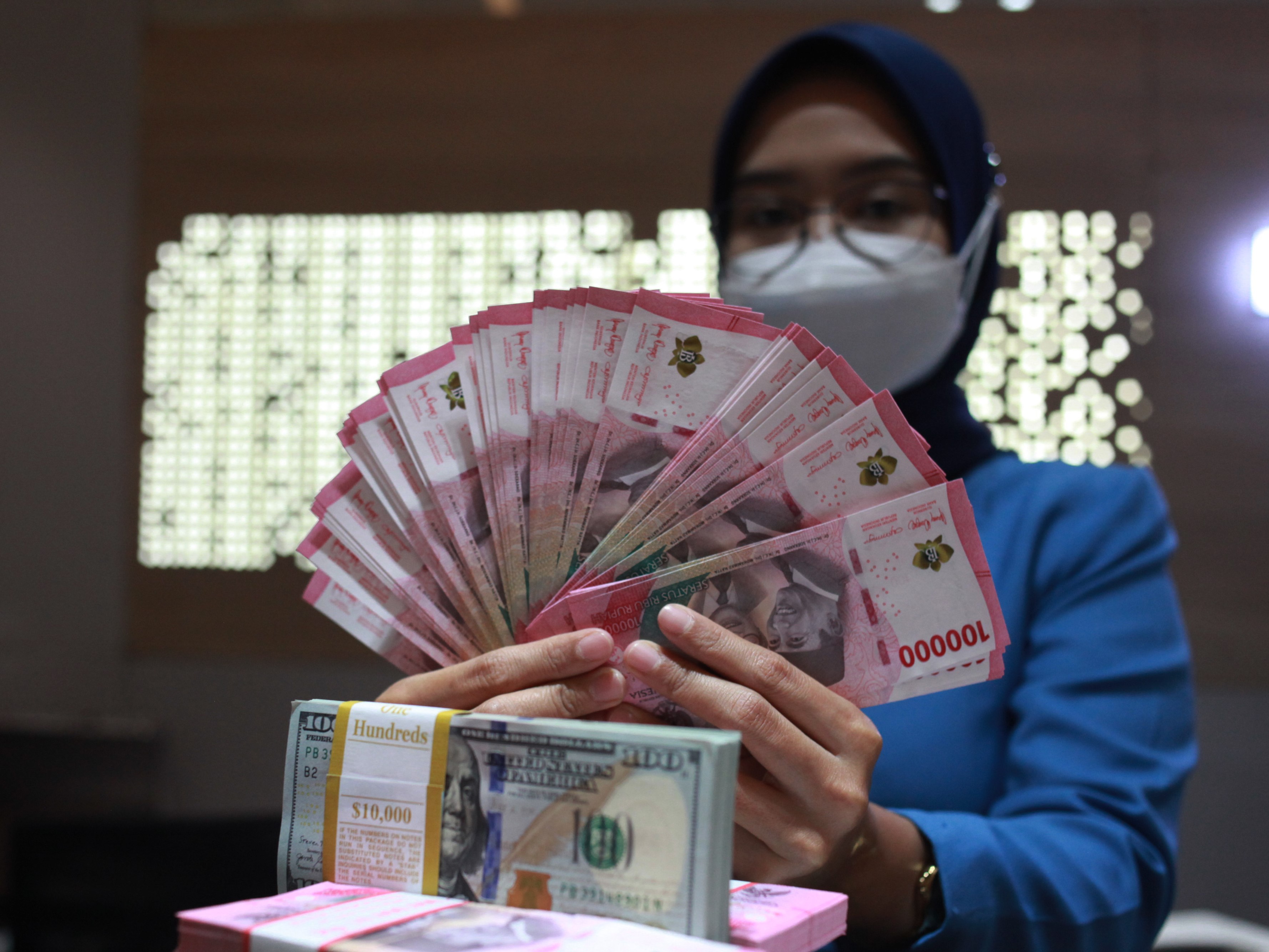 Petugas menunjukkan uang dolar AS dan uang rupiah di salah satu kantor cabang PT Bank Mandiri Persero Tbk, Jakarta, Selasa (31/1/2023).