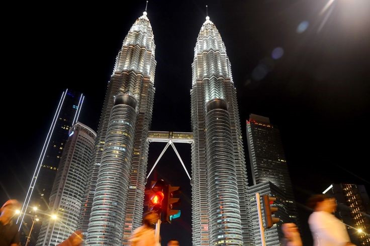 Warga melewati menara kembar Petronas (KLCC) di Kuala Lumpur, Malaysia
