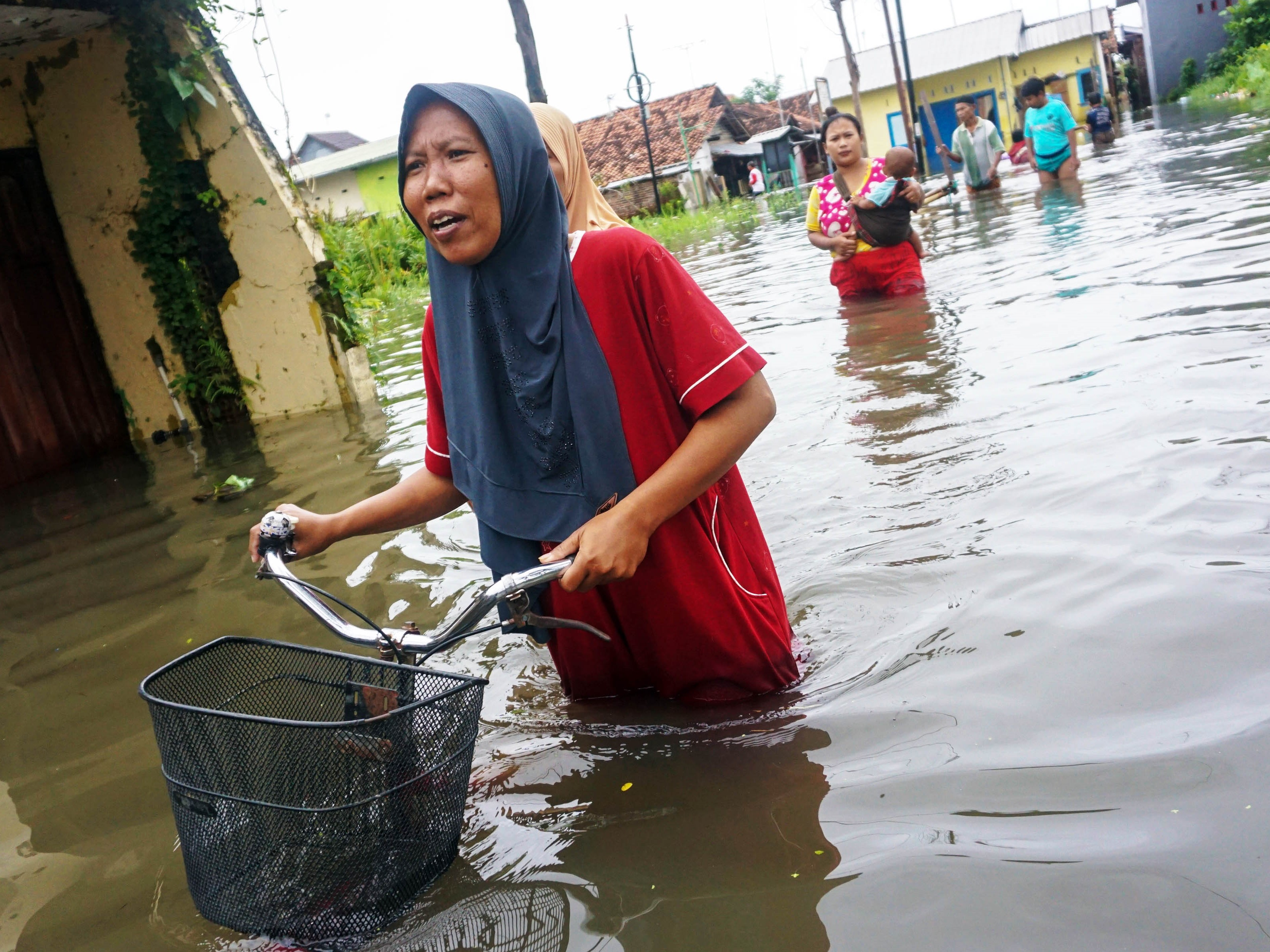 Warga berjalan melewati banjir di Tirto, Pekalongan, Jawa Tengah, Kamis (23/2/2023).