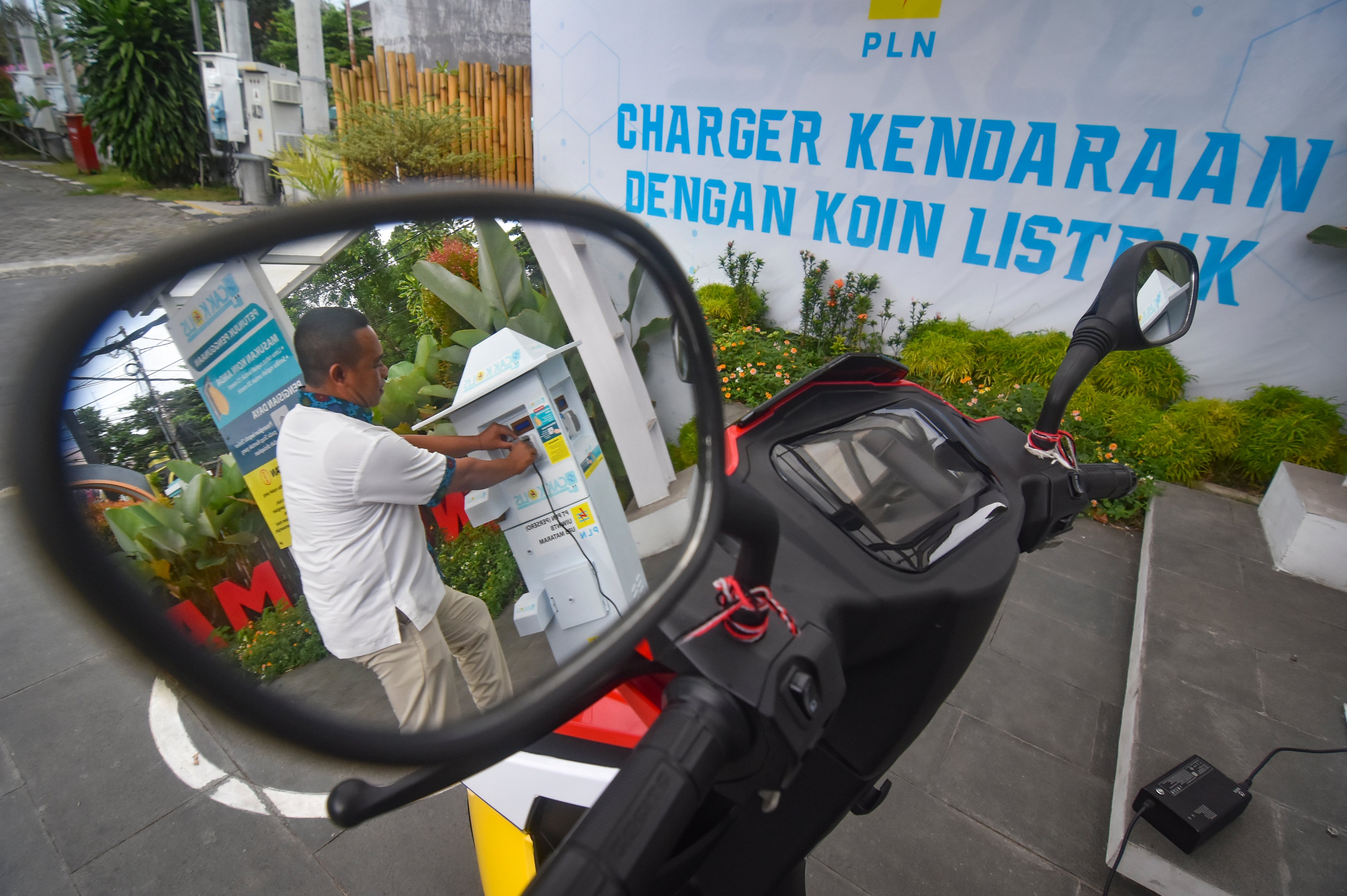 Warga mengisi daya baterai sepeda motor listriknya di SPKLU Charger kendaraan dengan koin listrik (Cak Kolis) di Mataram