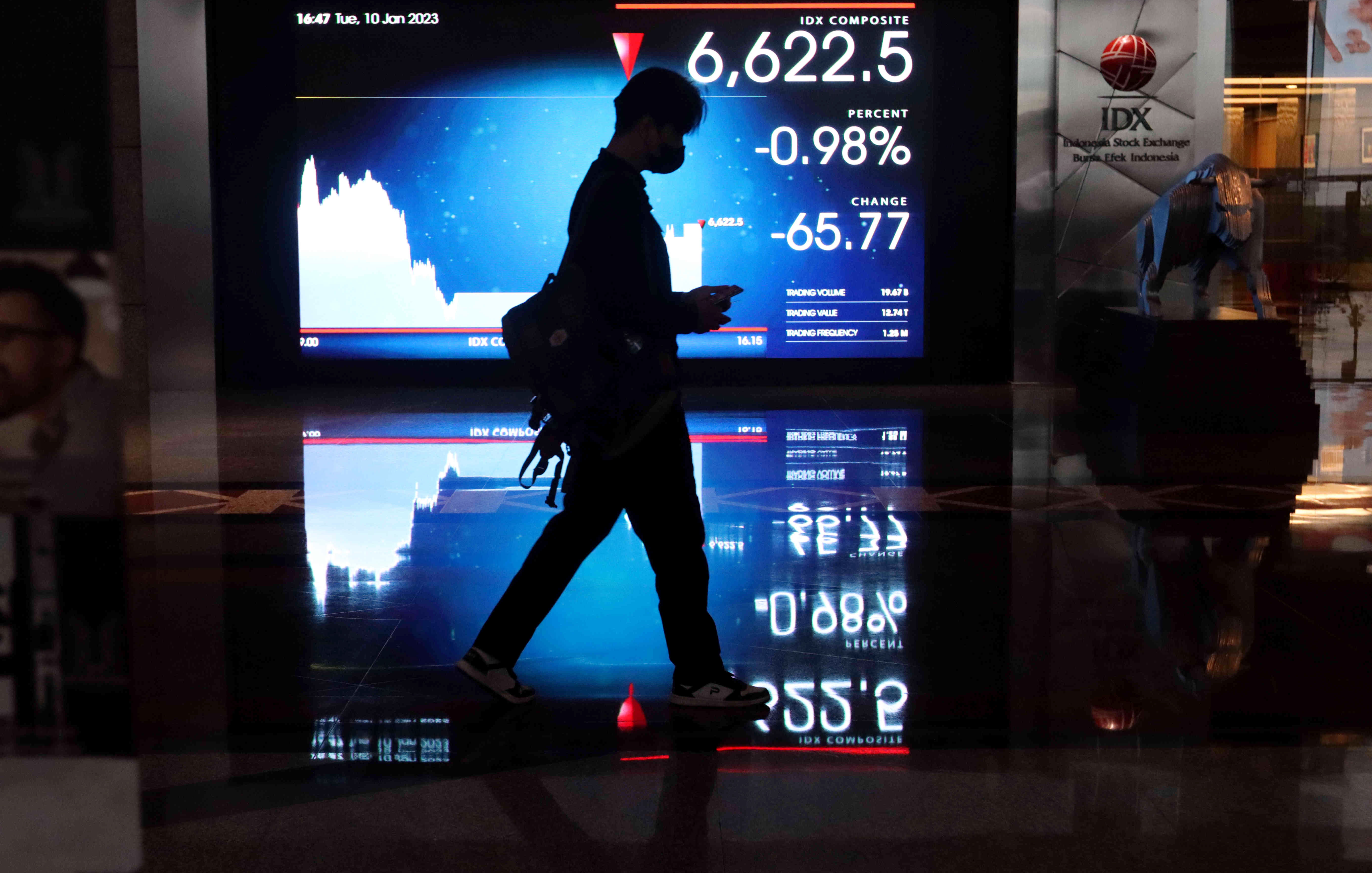 Ilustrasi: seorang melintas di dekat monitor pergerakan perdagangan saham di Bursa Efek Indonesia (BEI), Jakarta, Selasa (10/1/2023). 
