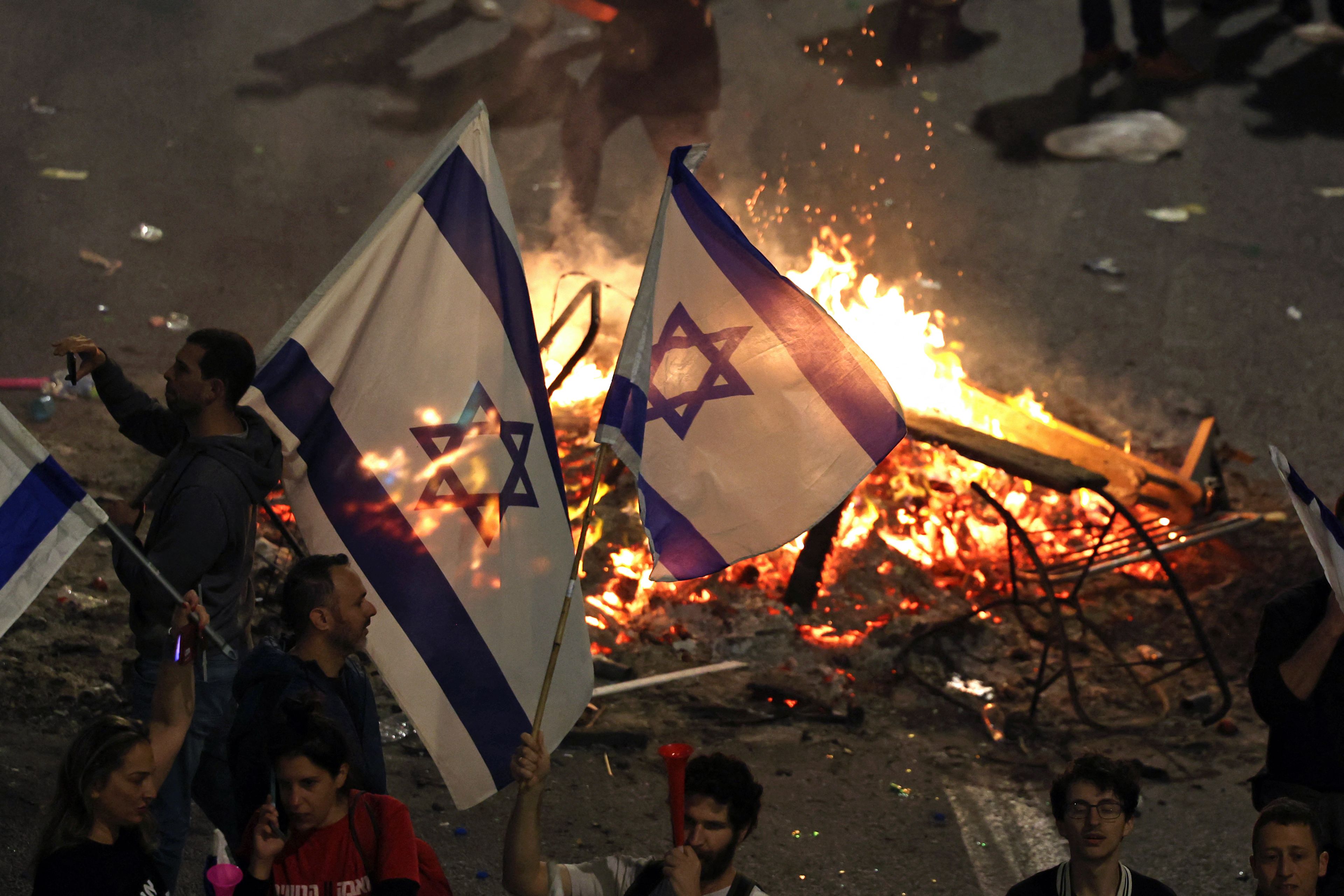 Para pengunjuk rasa di Tel Aviv menutup jalan dan menyalakan api di jalan utama di ibu kota tersebut pada 26 Maret 2023.