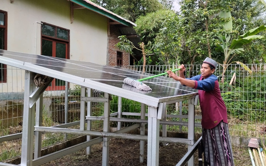 Seorang santri membersihkan panel surya di Pesantren Pertanian Yayasan Al Ma'hadul Islami 