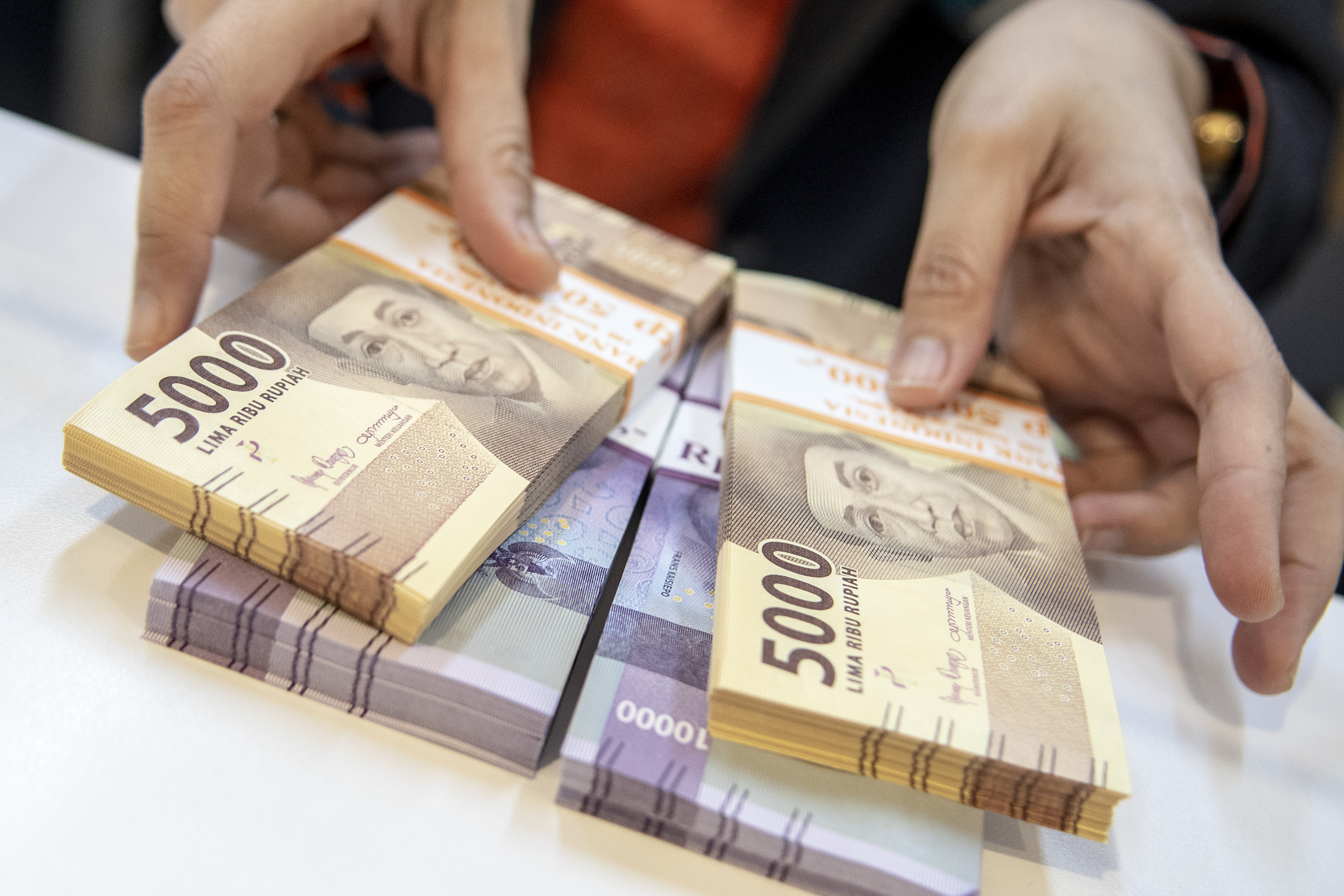 Petugas bank menunjukkan uang pecahan rupiah.