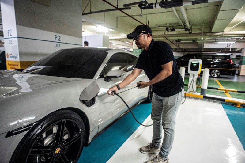 Pelanggan melakukan pengisian daya listrik ke mobilnya di Stasiun Pengisian Kendaraan Listrik Umum (SPKLU).