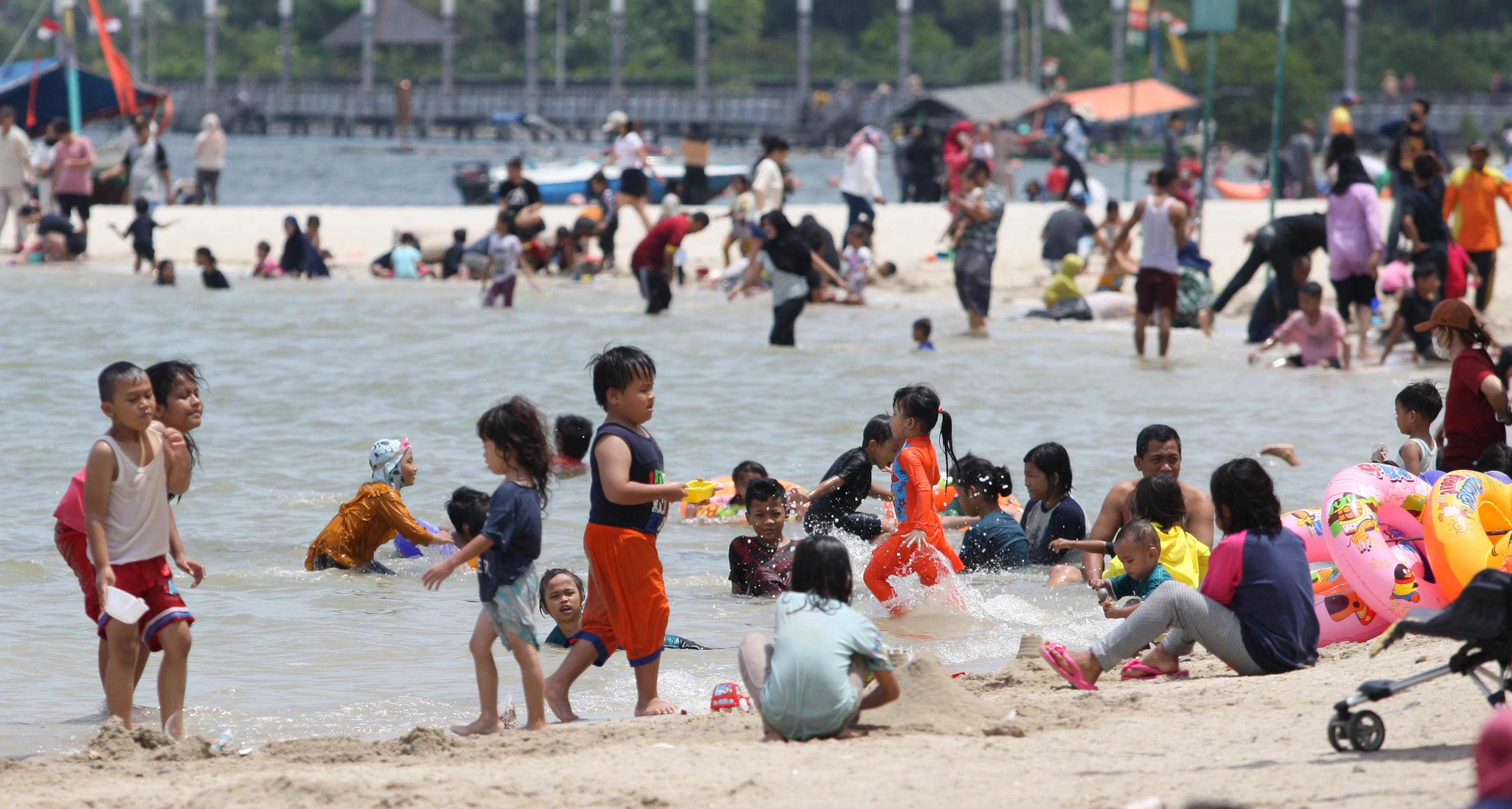  Pengunjung yang didominasi anak – anak bermain di Pantai Lagoon, Ancol, Jakarta.