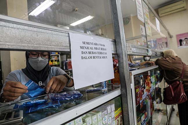 Petugas apotek menyiapkan obat di dekat tulisan perihal penghentian sementara penjualan obat sirop di apotek Wisnu, Ciledug, Kota Tangerang.