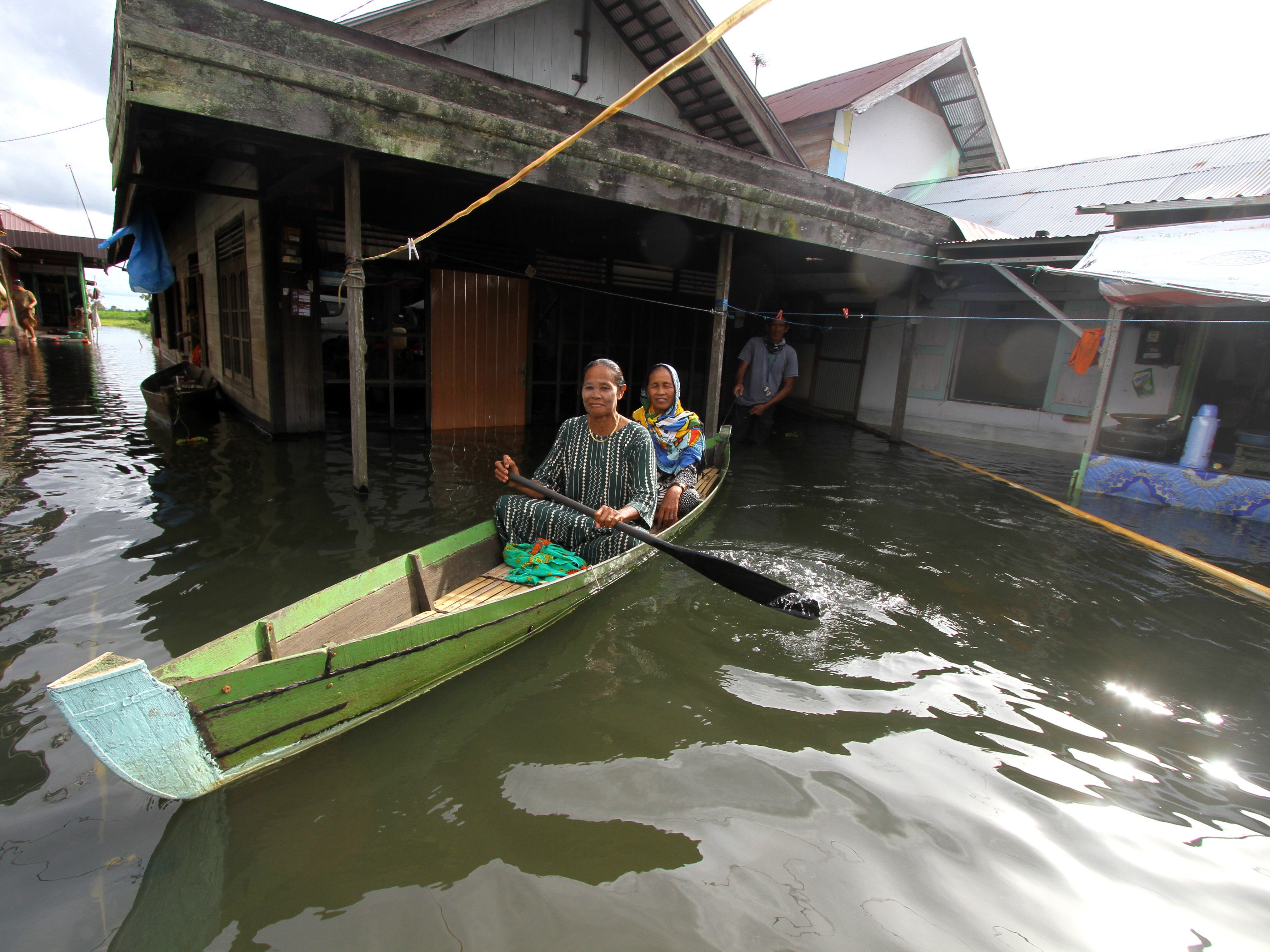 Dua orang menggunakan perahu saat keluar rumah yang terendam banjir di Desa Sungai Rangas Ulu, Kabupaten Banjar, Kalsel, Minggu (5/3).