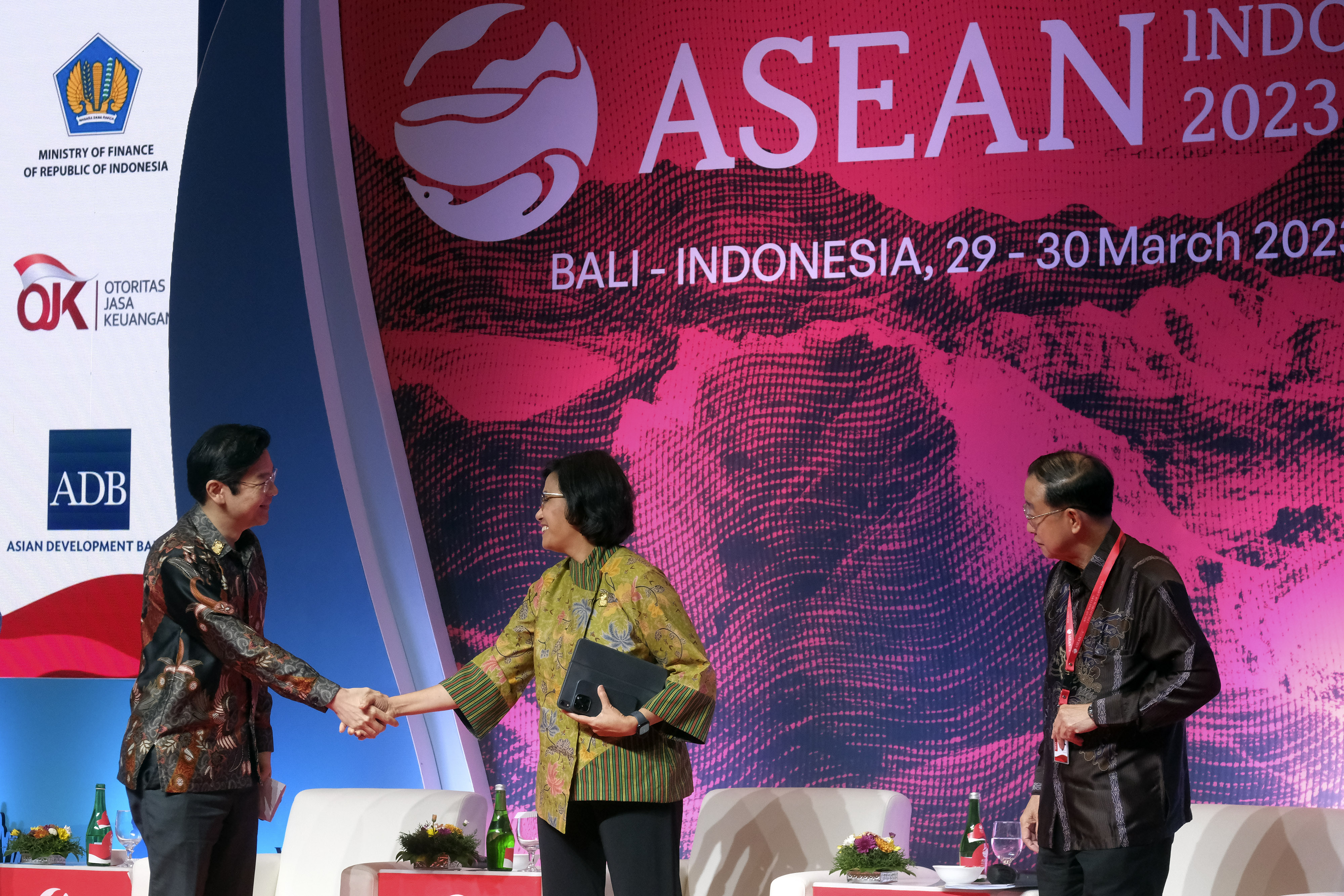 Menkeu Sri Mulyani (tengah) berjabat tangan dengan Menkeu Singapura Lawrence Wong (kiri) dalam pertemuan di Bali, 30 Maret 2023.