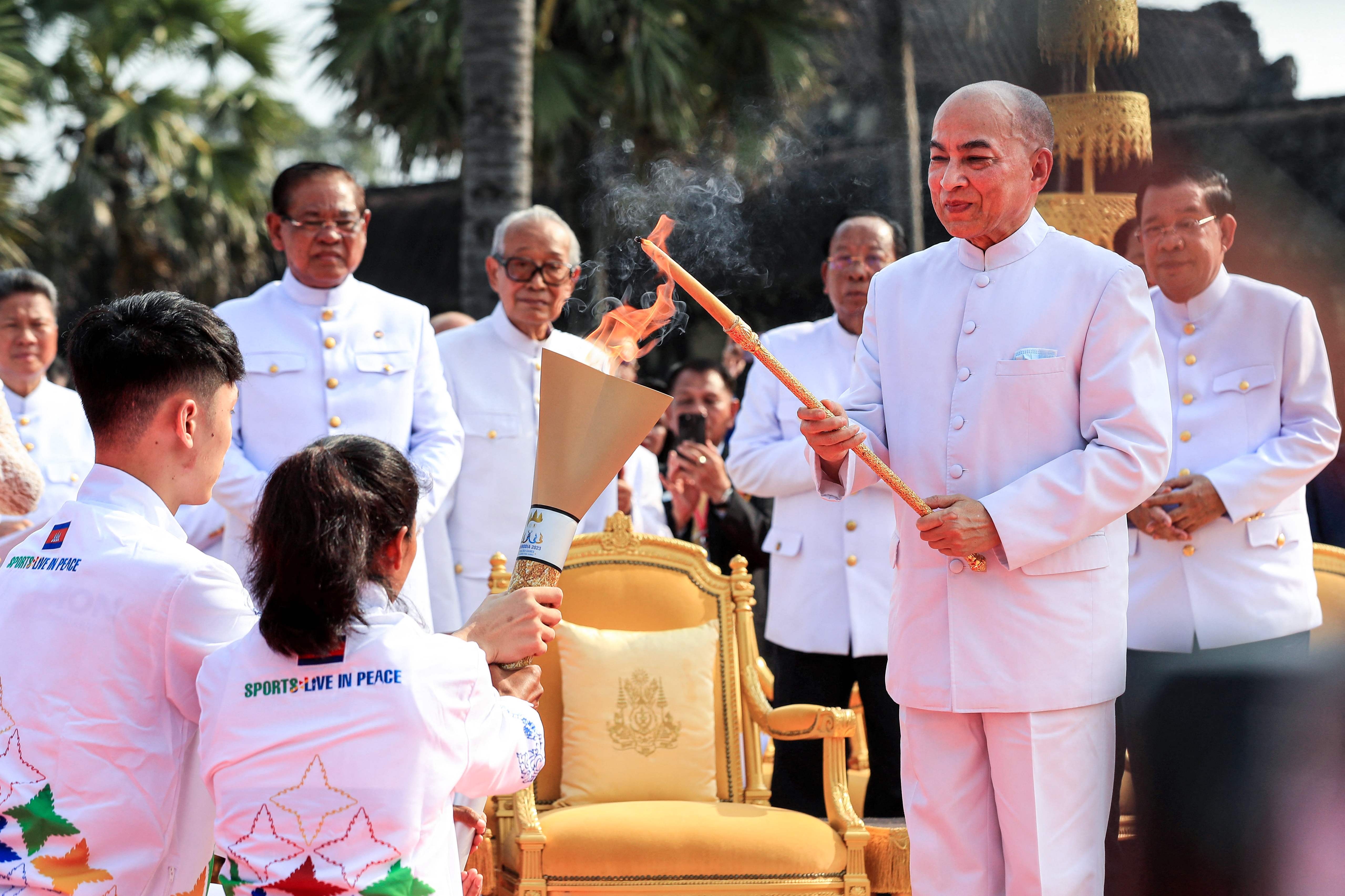 Raja Kamboja Norodom Sihamoni (kedua dari kanan) menyalakan obor dengan lilin menyala sebelum dibawa rombongan pembawa obor SEA Games ke-32.
