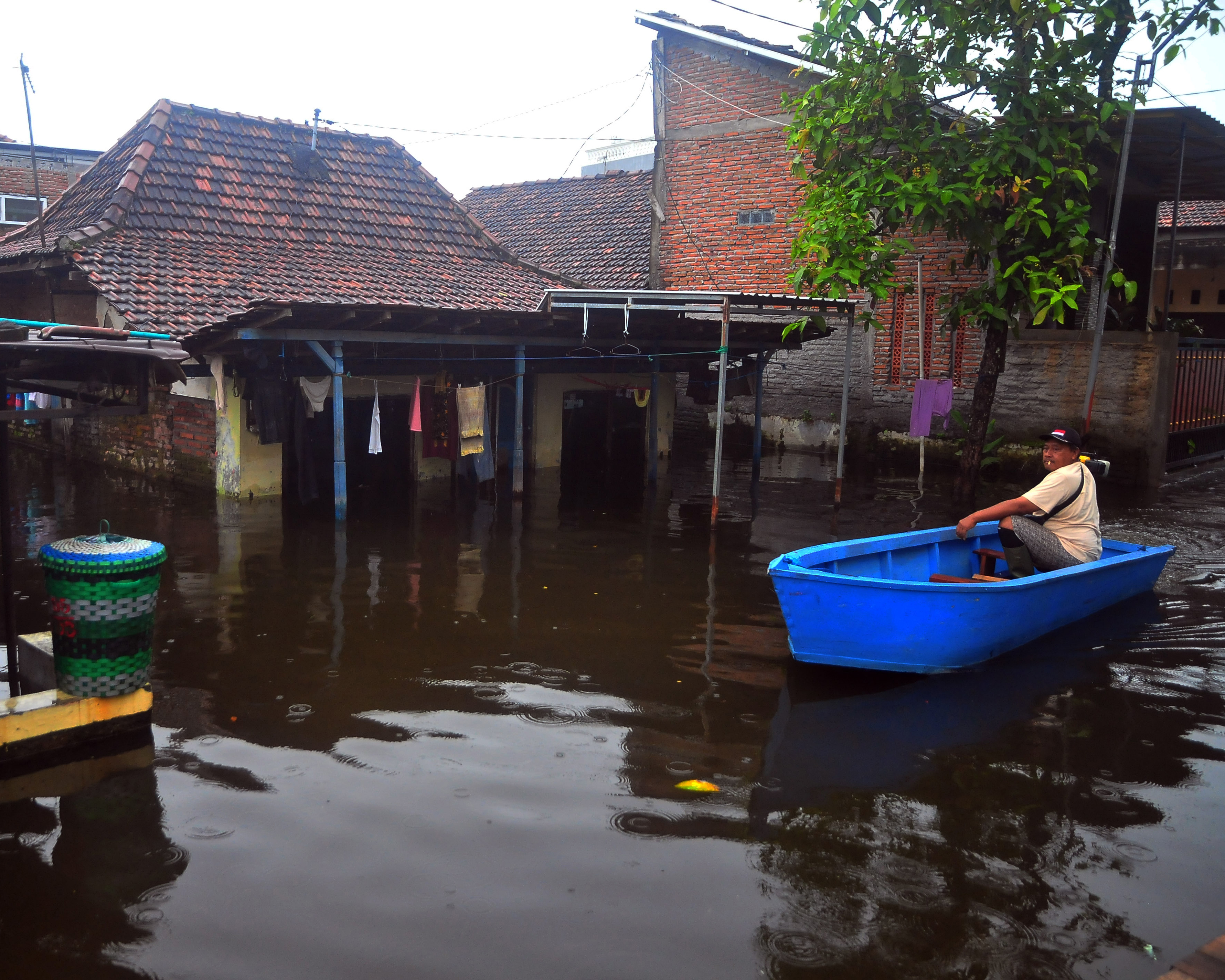 Warga menggunakan perahu melintasi jalan yang tergenang banjir di Dukuh Tanggulangin, Jati Wetan, Kudus, Jawa Tengah, Jumat (24/2).