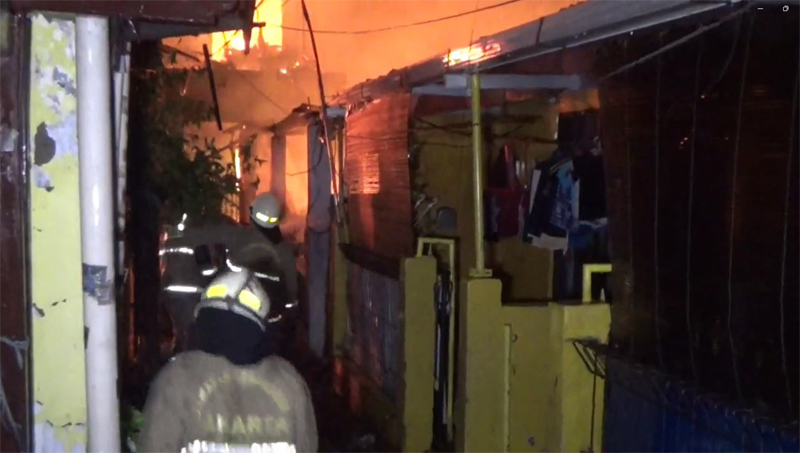 Pemadam kebakarna berupaya memadamkan api di Kampung Jembatan, Cakung.