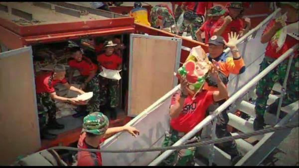 Sejumlah prajurit TNI tengah mengangkut bantuan pangan.