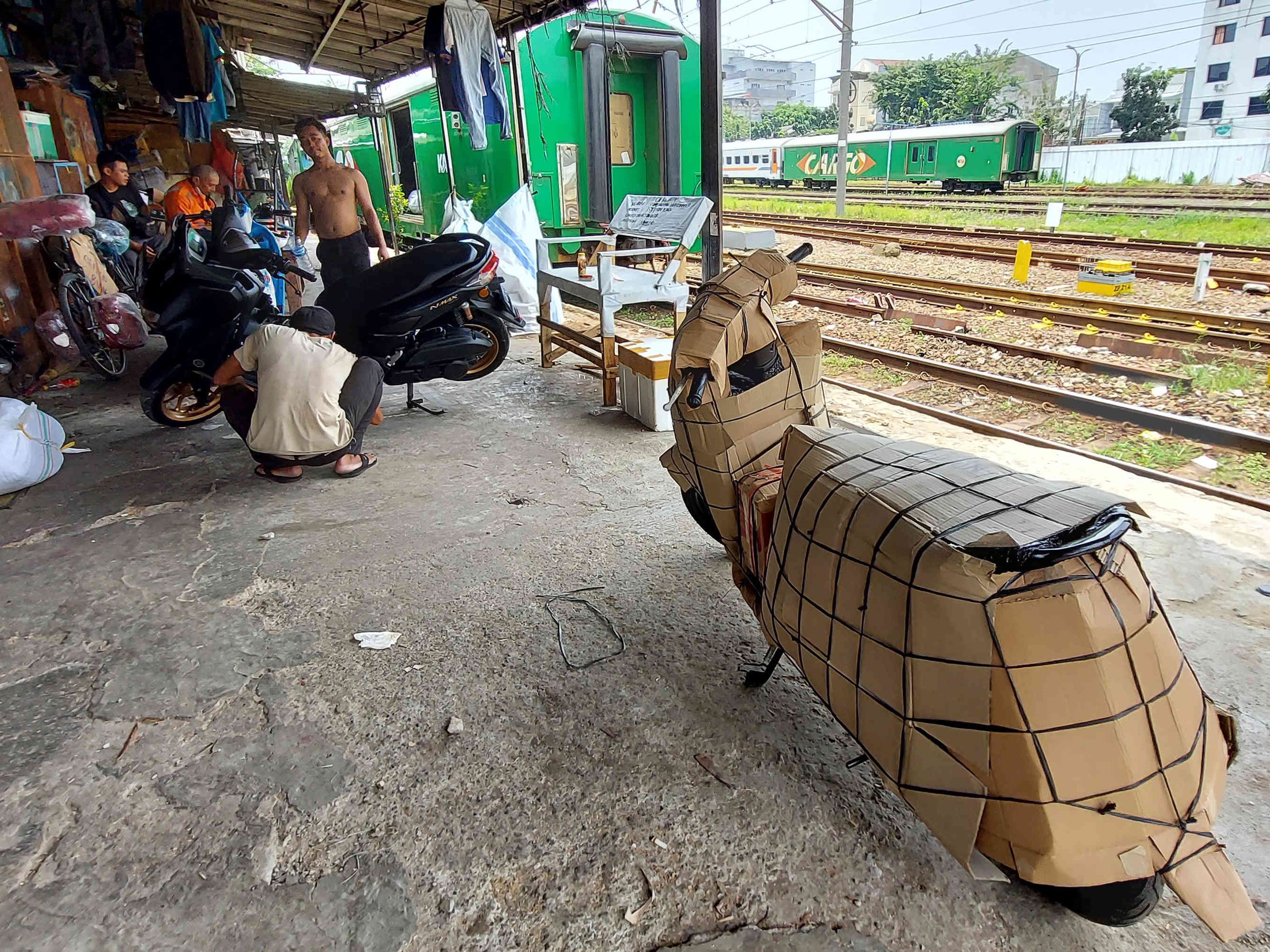 Pekerja menyiapkan sepeda motor untuk dipaketkan ke kereta di kawasan Stasiun Pasar Senen, Jakarta, Selasa (22/3/2023).