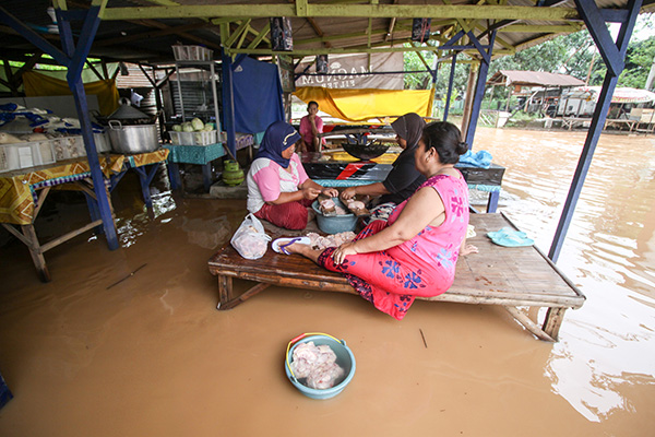 Warga beraktivitas di tengah kepungan banjir di Pasuruan, Jawa Timur.