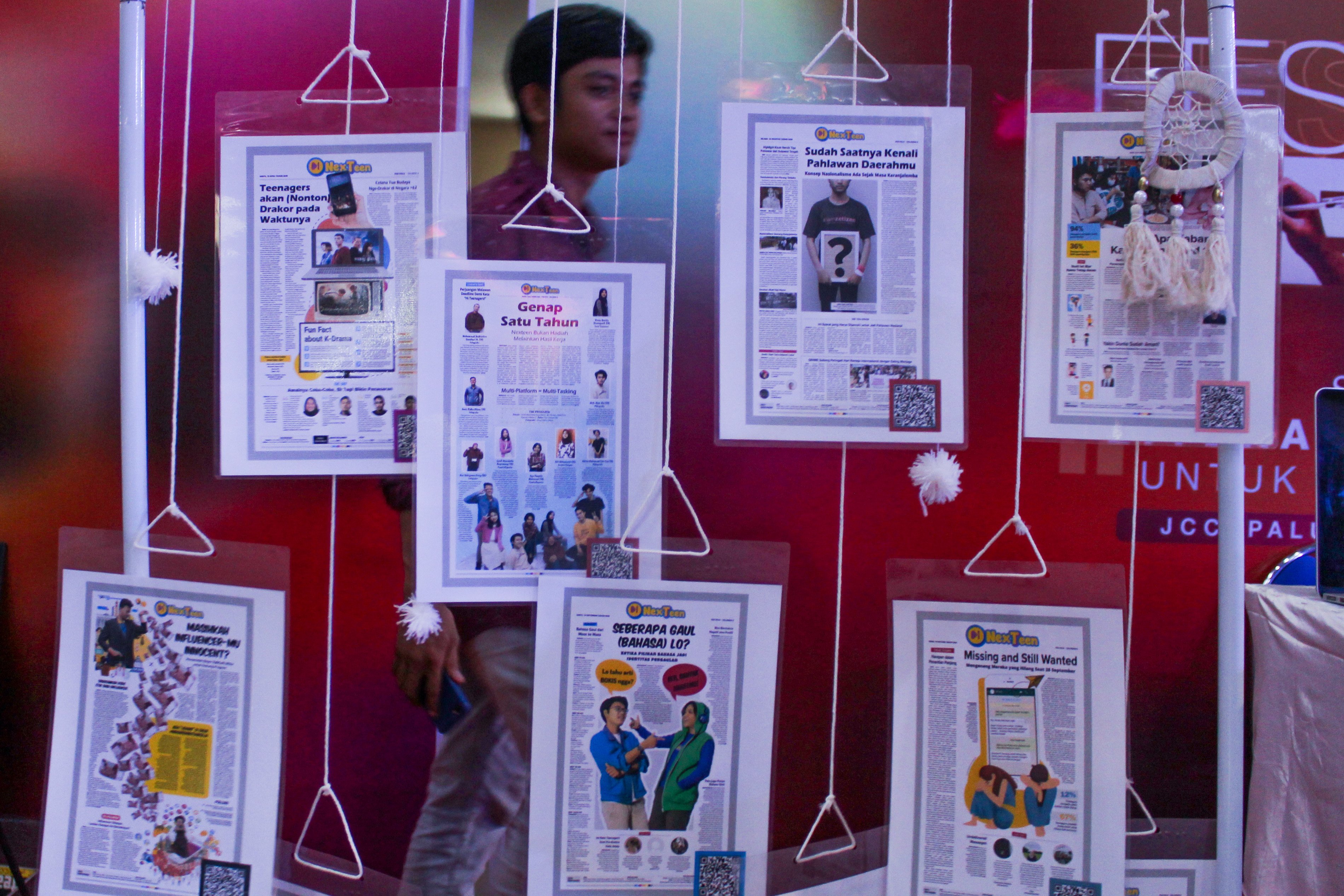 Pengunjung melintas di belakang contoh koran digital pada Festival Literasi Media Digital di Palu, Sulawesi Tengah, Jumat (9/12/2022).