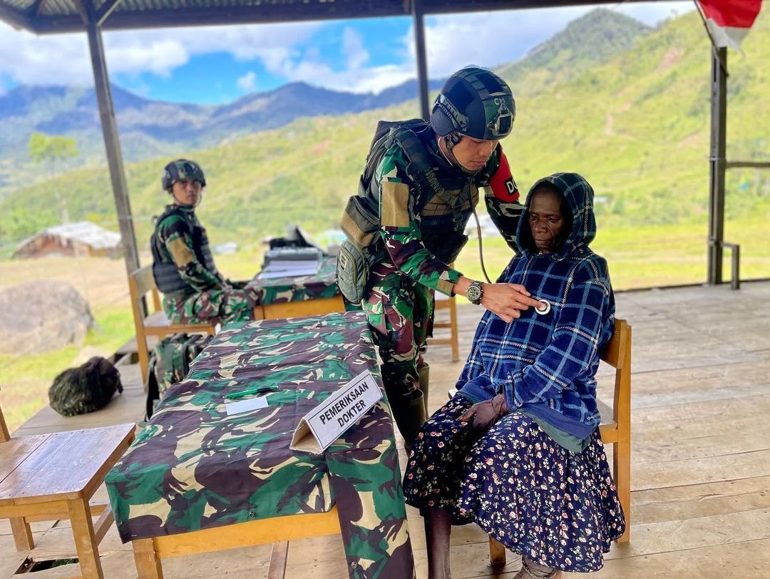 Salah seorang prajurit TNI tengah memeriksa kesehatan seorang warga Papua.