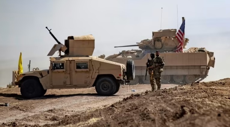 Tentara Kurdi dari Pasukan Demokratik Suriah (SDF) berdiri di dekat kendaraan militer AS di Provinsi Hasakah, Suriah.