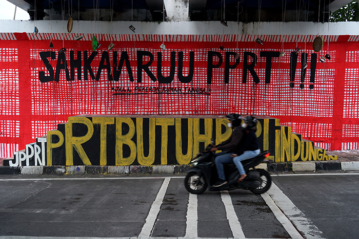 Warga melintas di dekat mural yang bertuliskan 