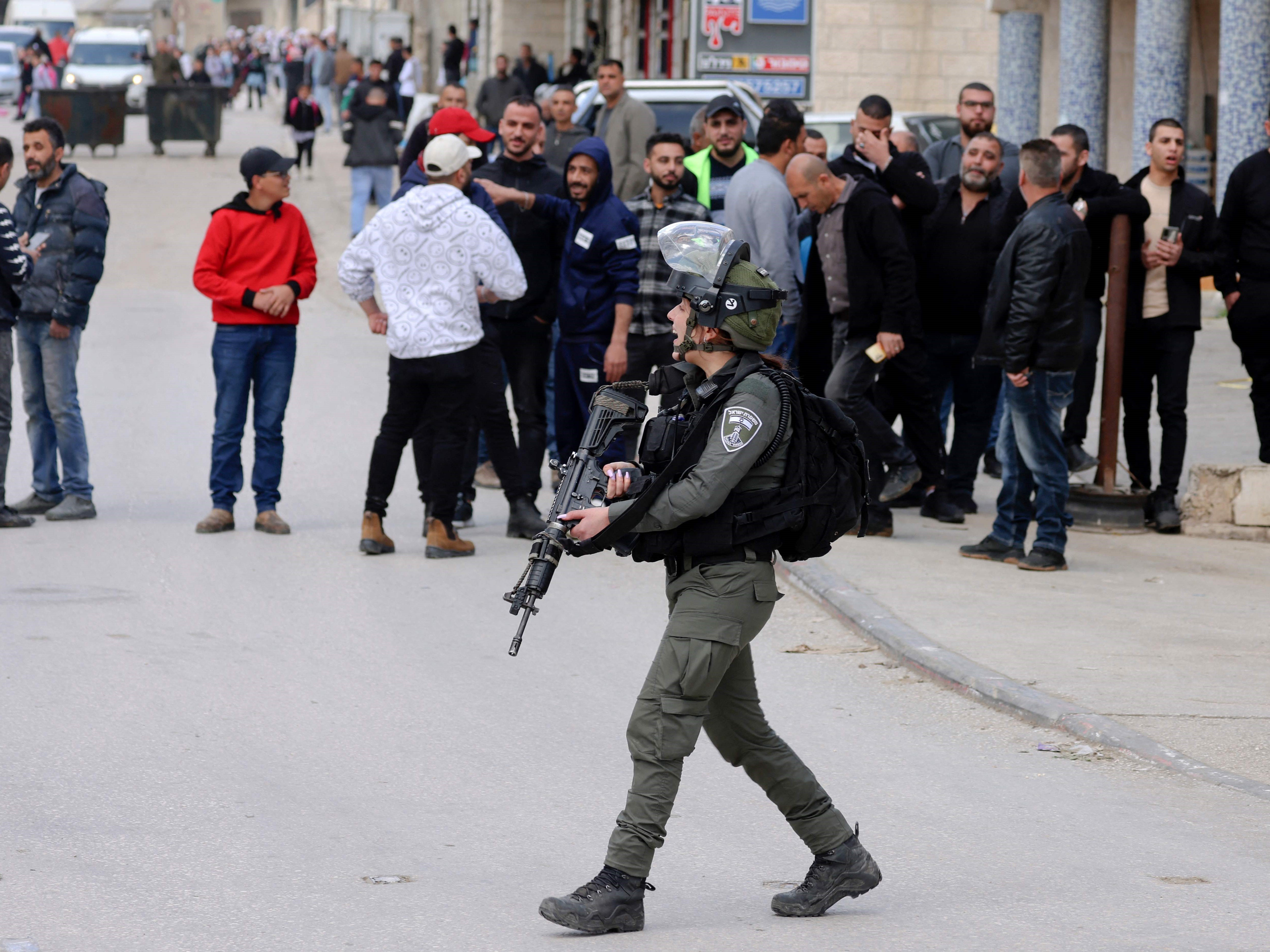 Warga menyaksikan tentara Israel berpatroli di kota Huwara, Tepi Barat yang diduduki, pada 26 Maret 2023.