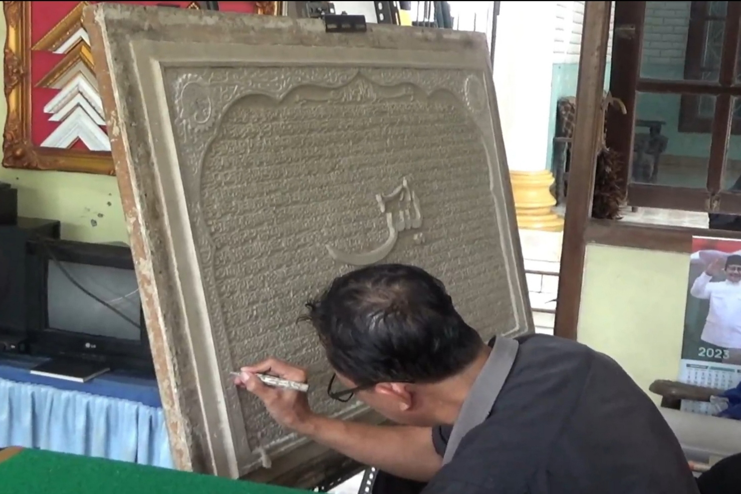 Seorang warga Sidoarjo, Jawa Timur tengah melukis kaligrafi.