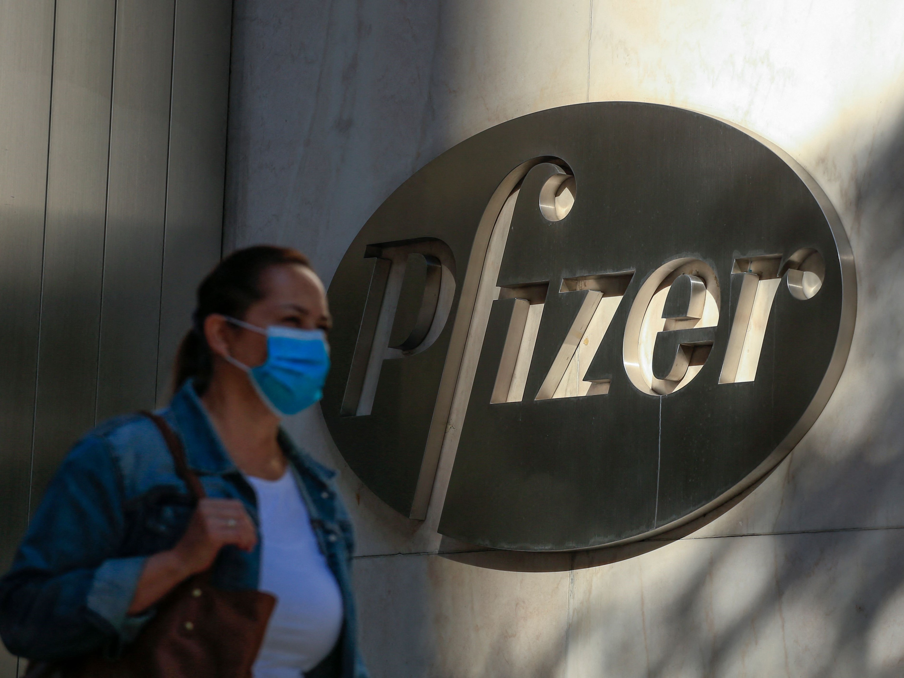 Seorang wanita mengenakan masker saat berjalan melewati kantor pusat dunia Pfizer di New York.