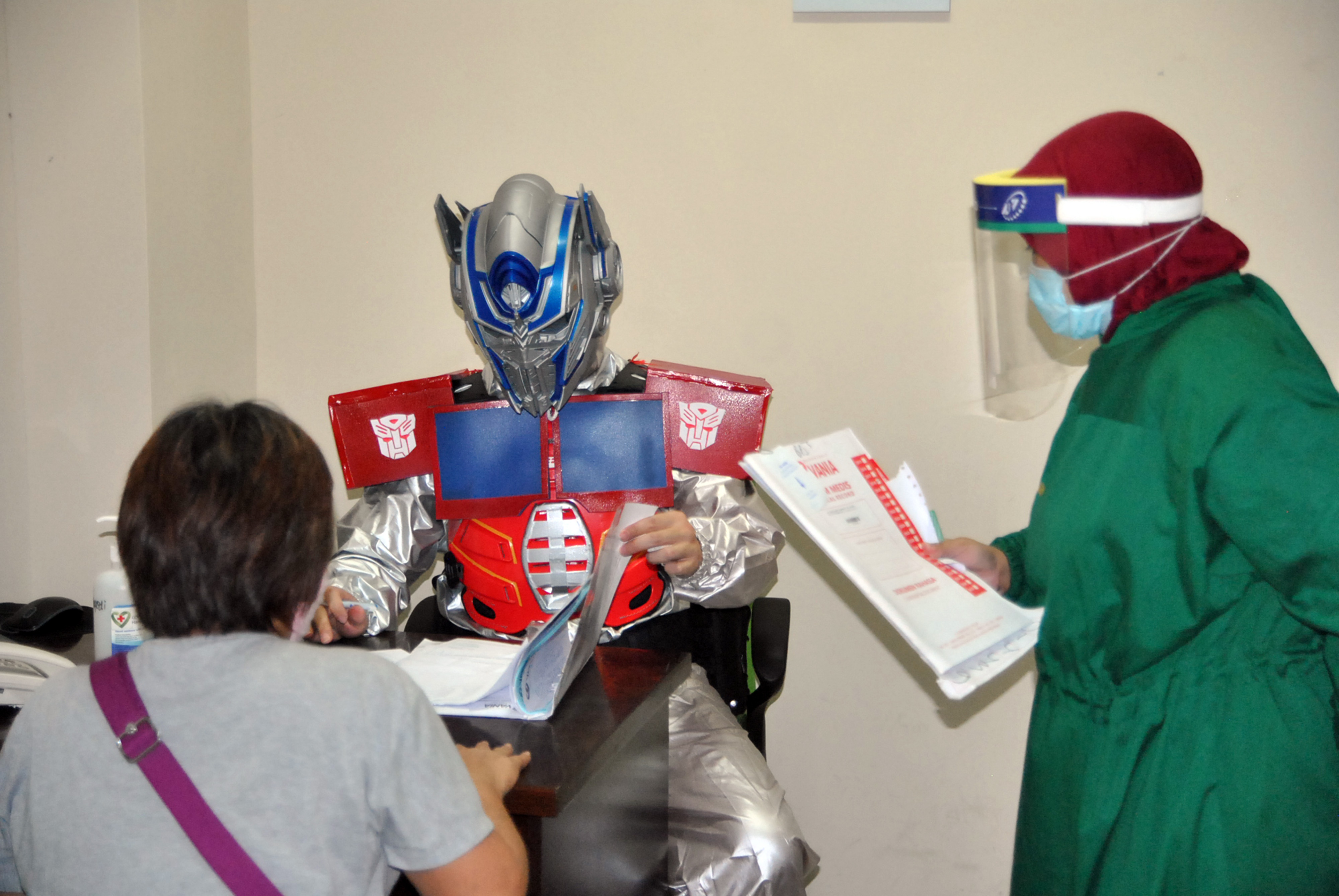 Seorang dokter spesialis menggunakan alat pelindung diri (APD) kostum superhero Optimus Prime saat memeriksa pasien.