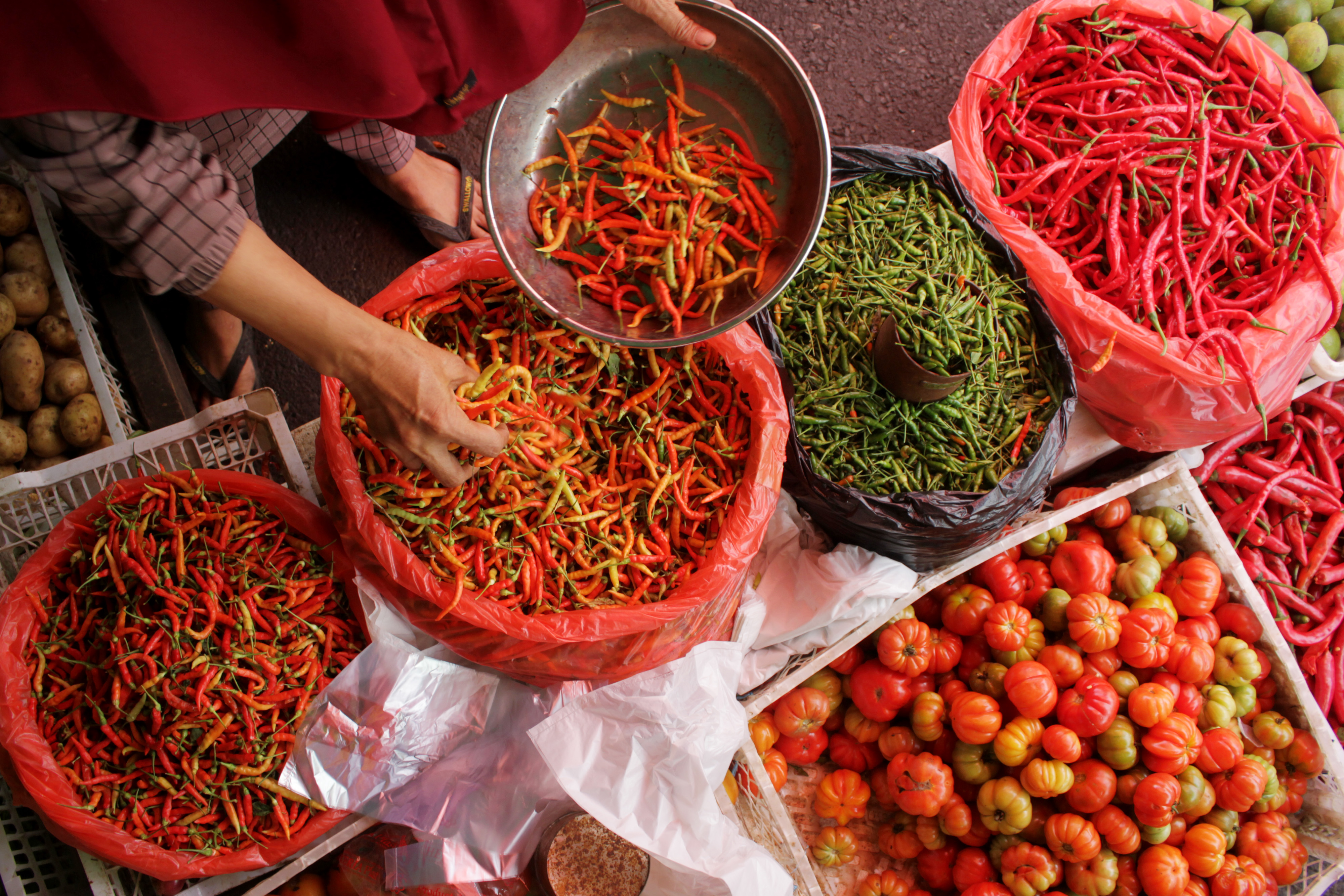 Pedagang melayani pembeli cabai rawit di Pasar Terong Makassar, Sulawesi Selatan, Kamis (8/4/2021).