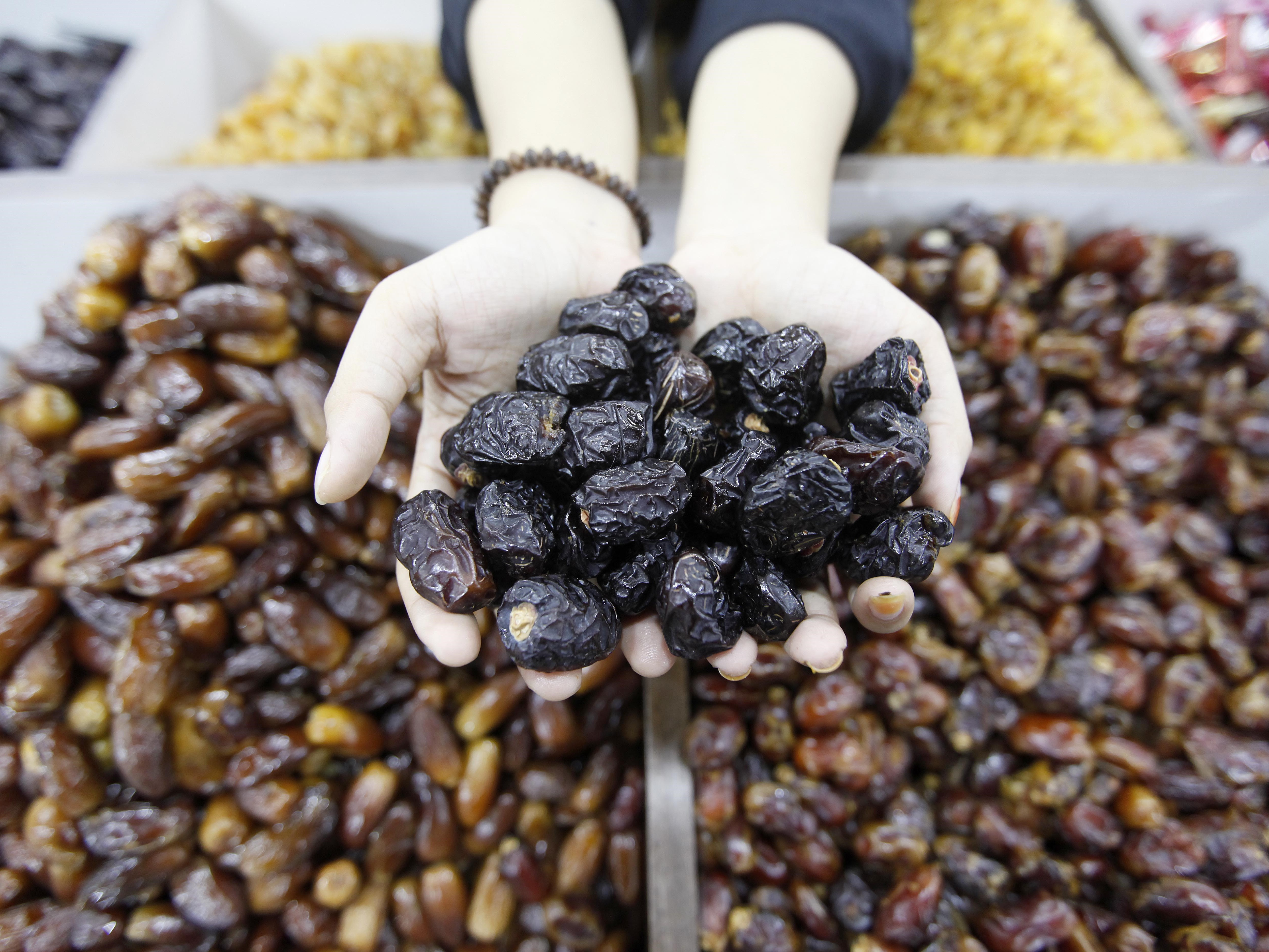 Pegawai toko menunjukkan kurma ajwa yang merupakan oleh-oleh khas haji dan umrah di kawasan Tanah Abang, Jakarta, Selasa (24/1/2023).