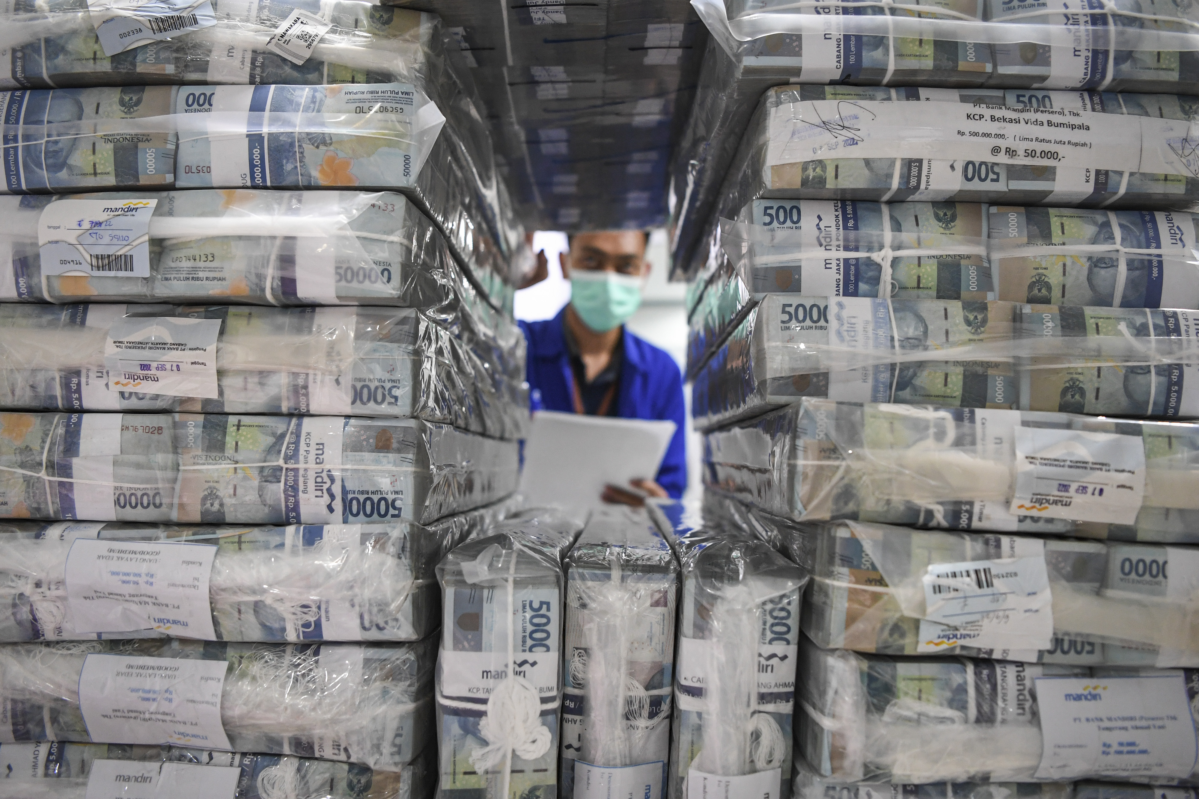 Petugas mengecek uang tunai sebelum didistribusikan ke bank dan ATM