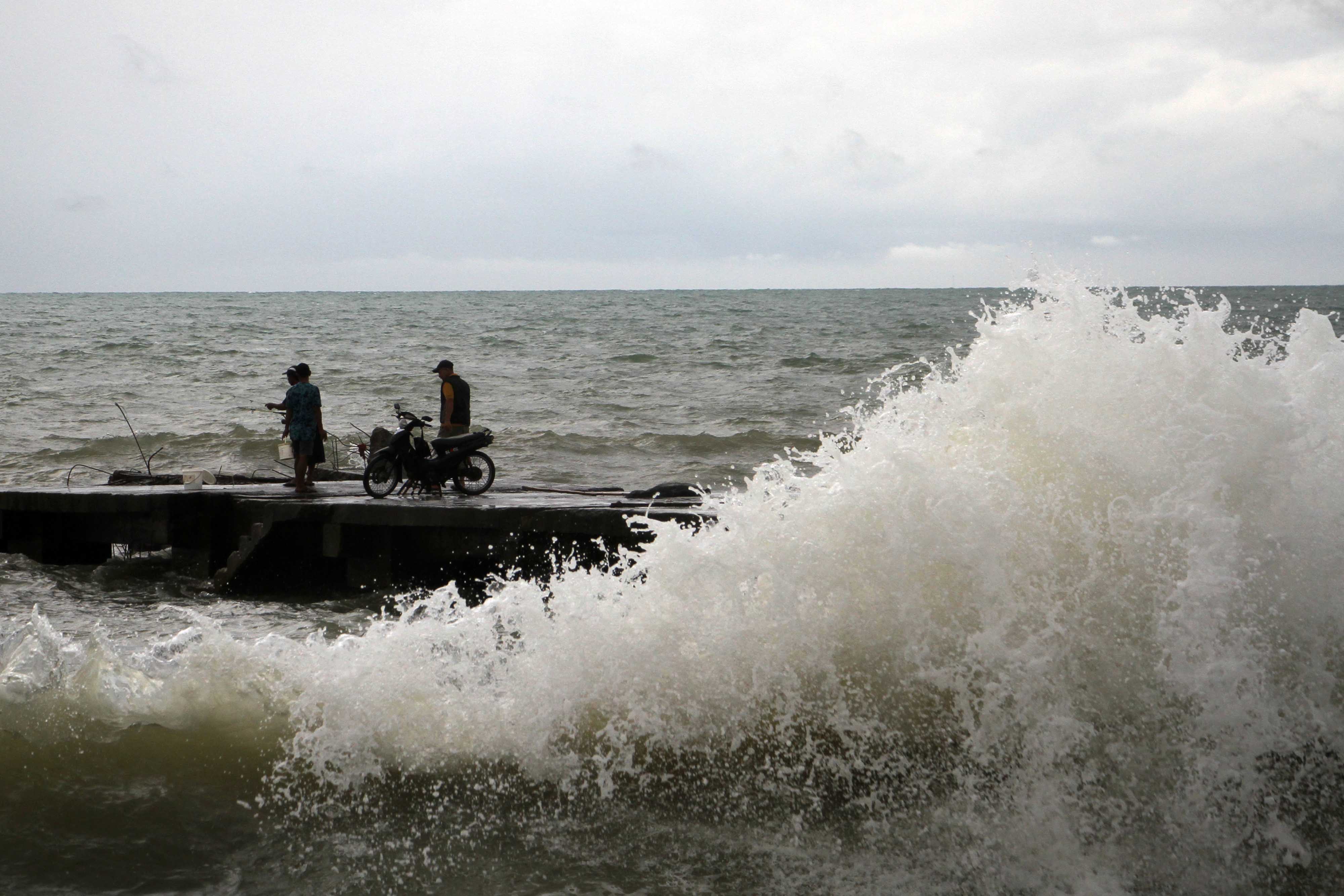 Warga melihat gelombang tinggi di dermaga Pangkalan Pendaratan Ikan (PPI) Beba, Kabupaten Takalar, Sulawesi Selatan