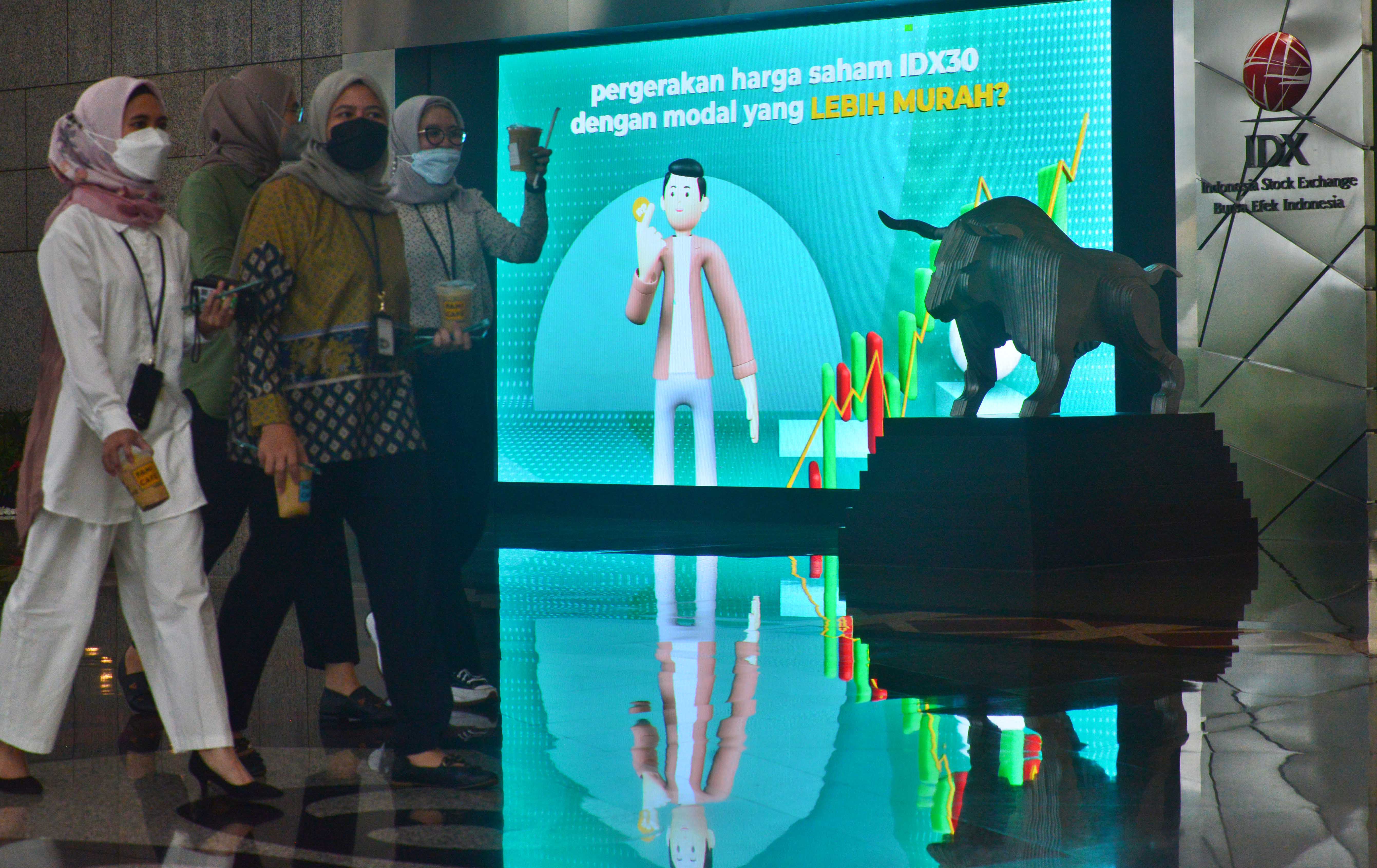 Pegawai berjalan di depan papan informasi di gedung Bursa Efek Indonesia di Jakarta.