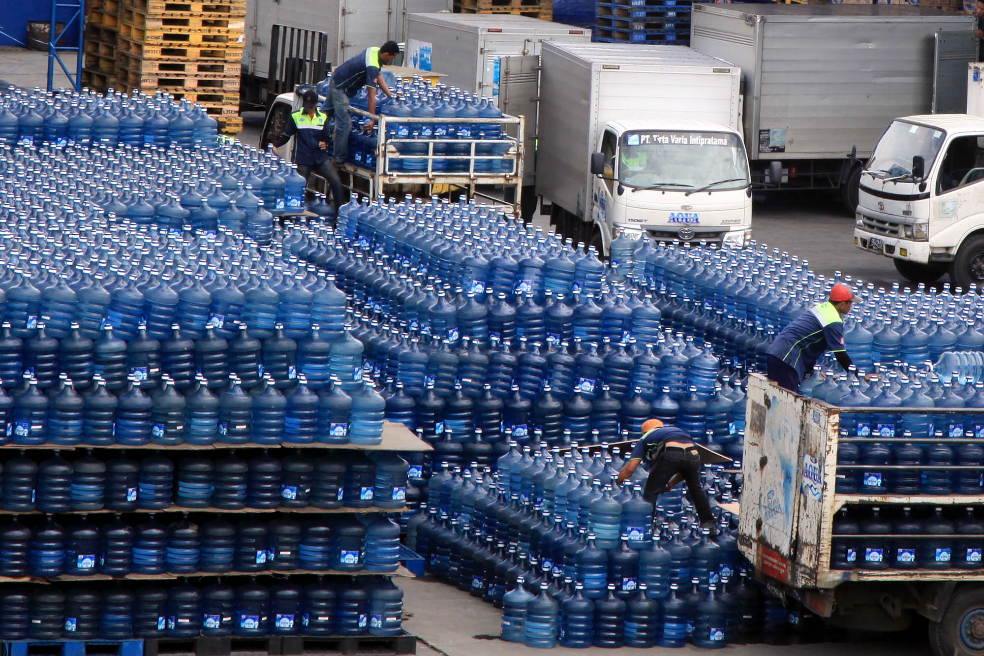 Pekerja tengah memuat air minum dalam kemasan ke truk 