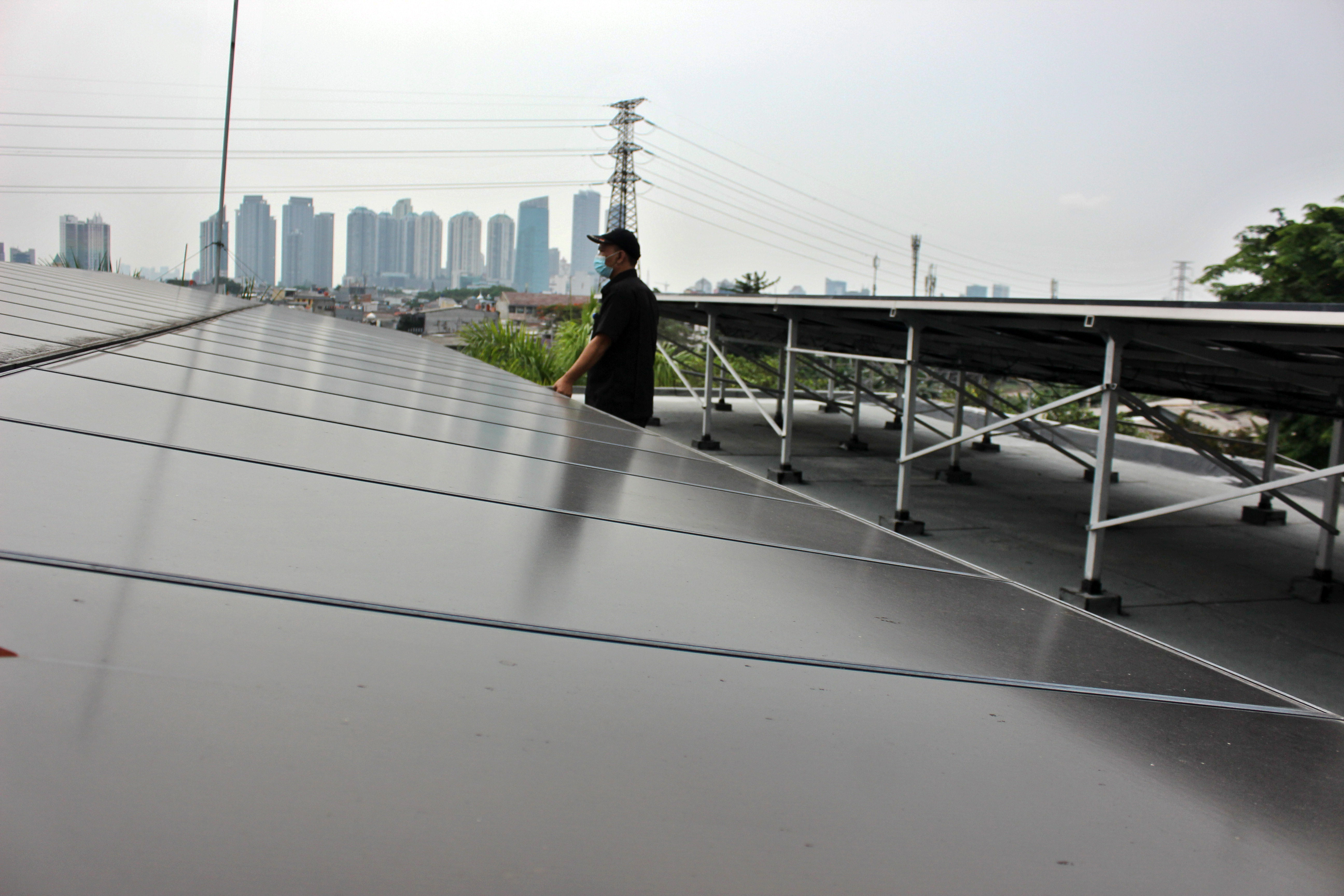 Ilustrasi: pekerja memeriksa panel pembangkit listrik tenaga surya (PLTS) di Gedung PPKD, Jakarta.