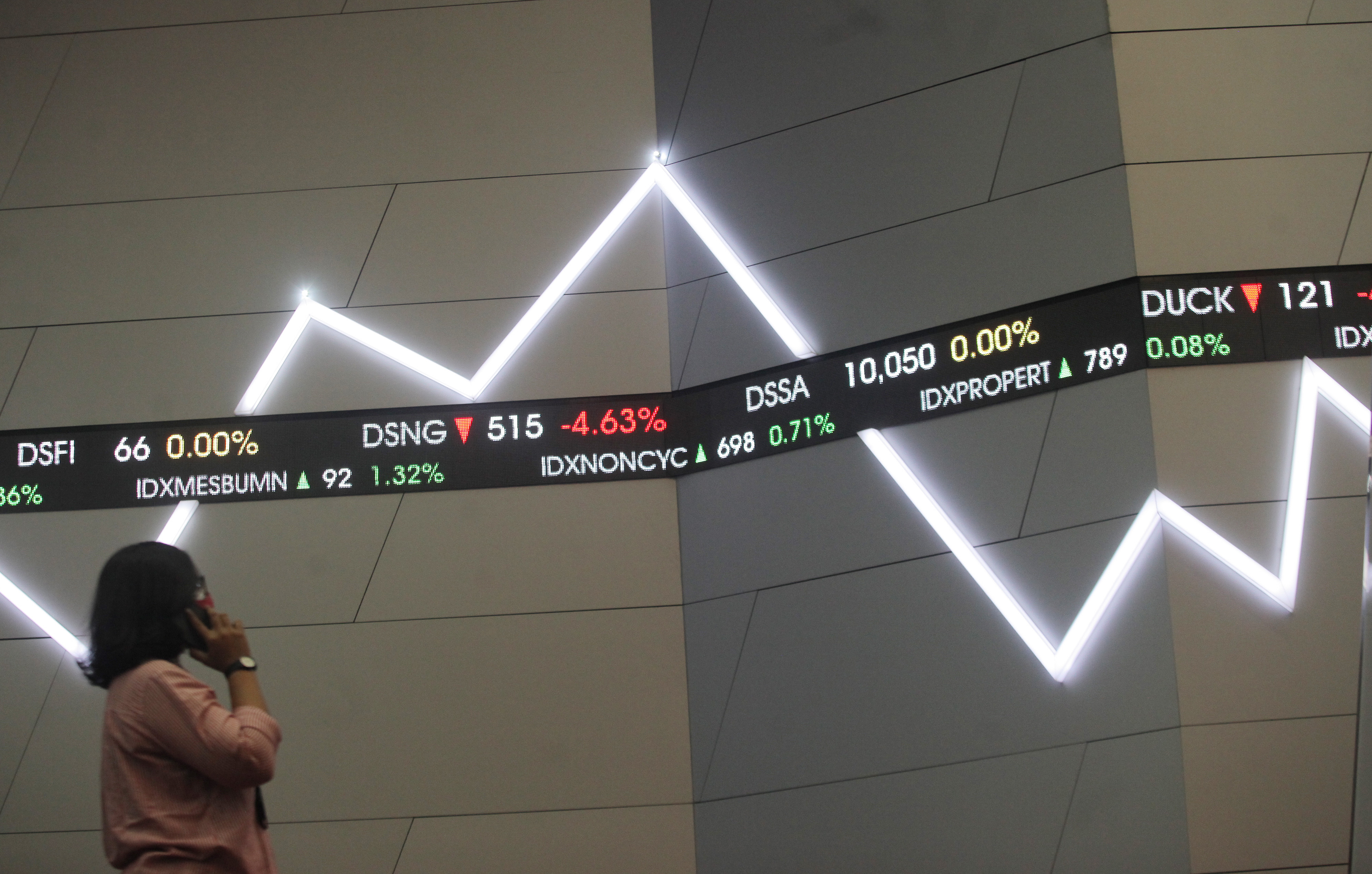  Karyawan melintas di dekat layar monitor pergerakan Indeks Harga Saham Gabungan (IHSG) di Bursa Efek Indonesia, Jakarta, Jumat (25/6/2021).